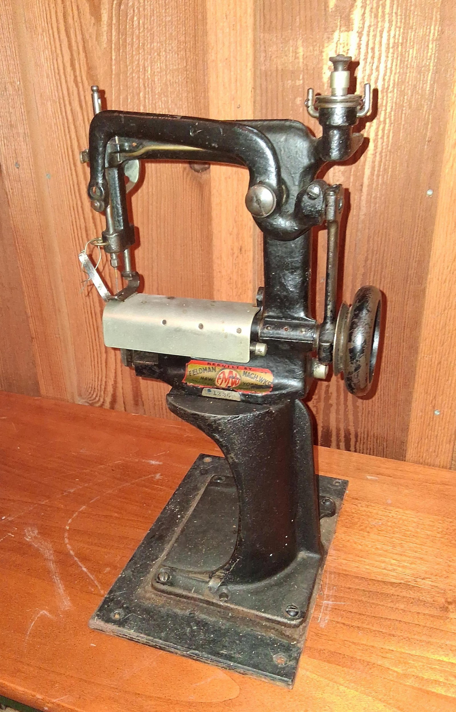 Feldman Millinery Cylinder Bed Sewing Machine: This is a specialized industrial millinery or straw braiding sewing machine rebuilt by Feldman Machine Works of New York. The machine features a heavy cast iron pedestal frame with a black japanned en