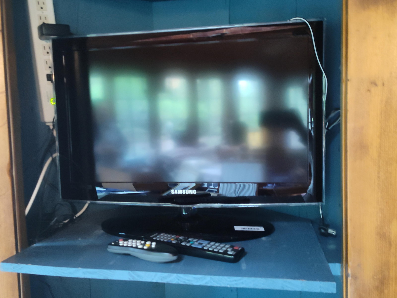 26 In Samsung Series 4 LED Television & 2 Remotes: A Samsung Series 4 LED television featuring a black bezel with a transparent acrylic border and an oval pedestal stand. The Samsung brand name is printed on the lower front bezel. The lot includes
