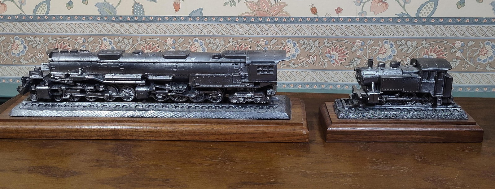 Michael Ricker Steam Locomotive Sculptures, Pair: Michael Ricker limited edition steam locomotive sculptures, dated 1993. This lot features two static scale model locomotives cast in pewter and mounted on wooden bases with a walnut finish. The