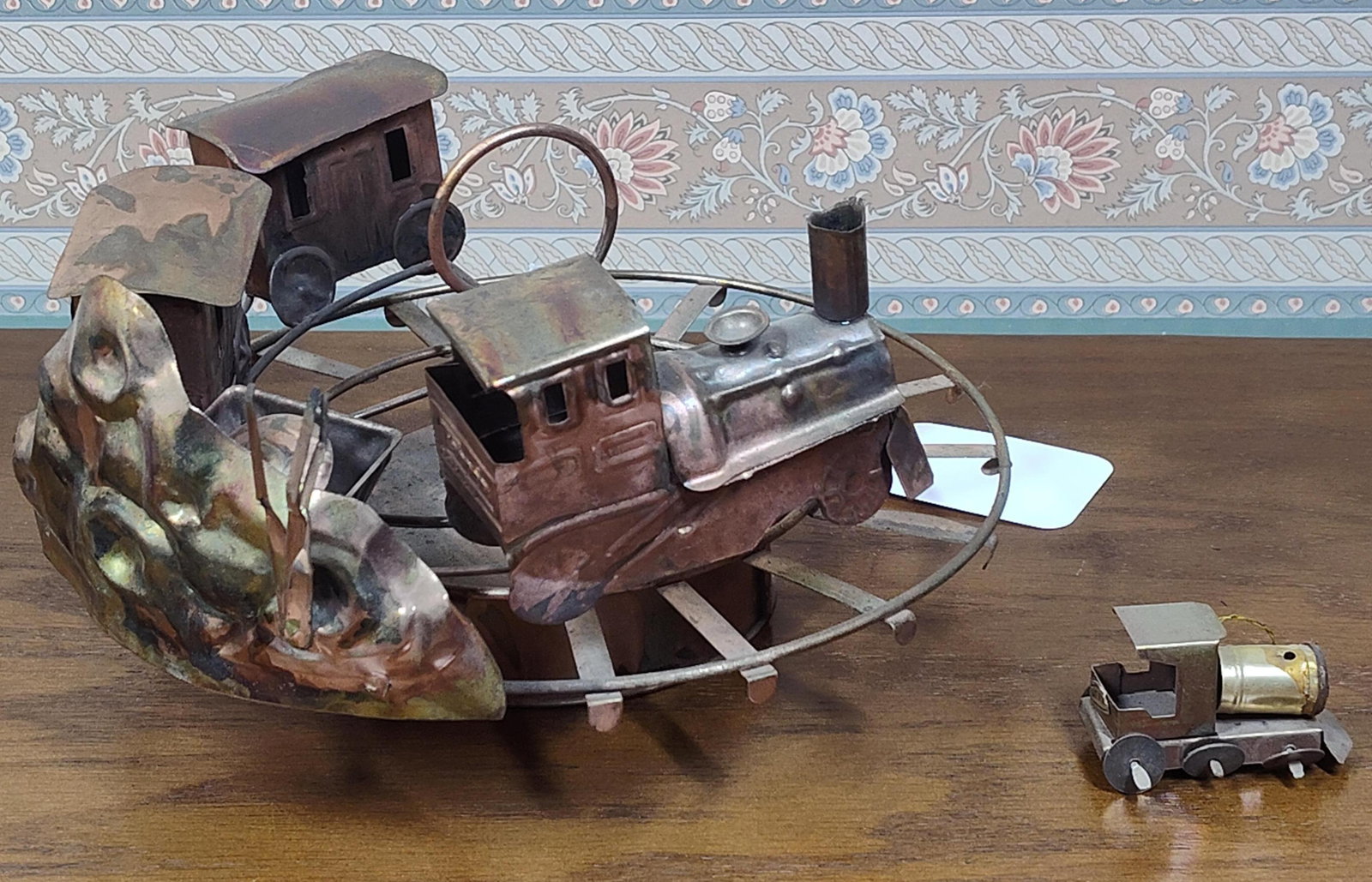 Pair Artisan Copper & Brass Mechanical Trains: A pair of vintage handcrafted metal mechanical displays featuring train motifs, designed in the style of mid-twentieth-century copper musical novelties. The primary assembly consists of a circular