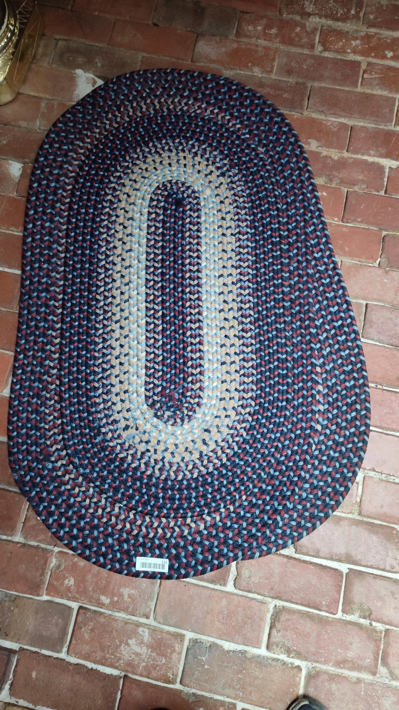 Pair Oval Braided Rugs, Navy, Burgundy & Tan: 48 and 38 inches long. A pair of matching oval braided rugs featuring a traditional American country-style design with concentric bands of color. Each rug is constructed from braided fiber strands, li