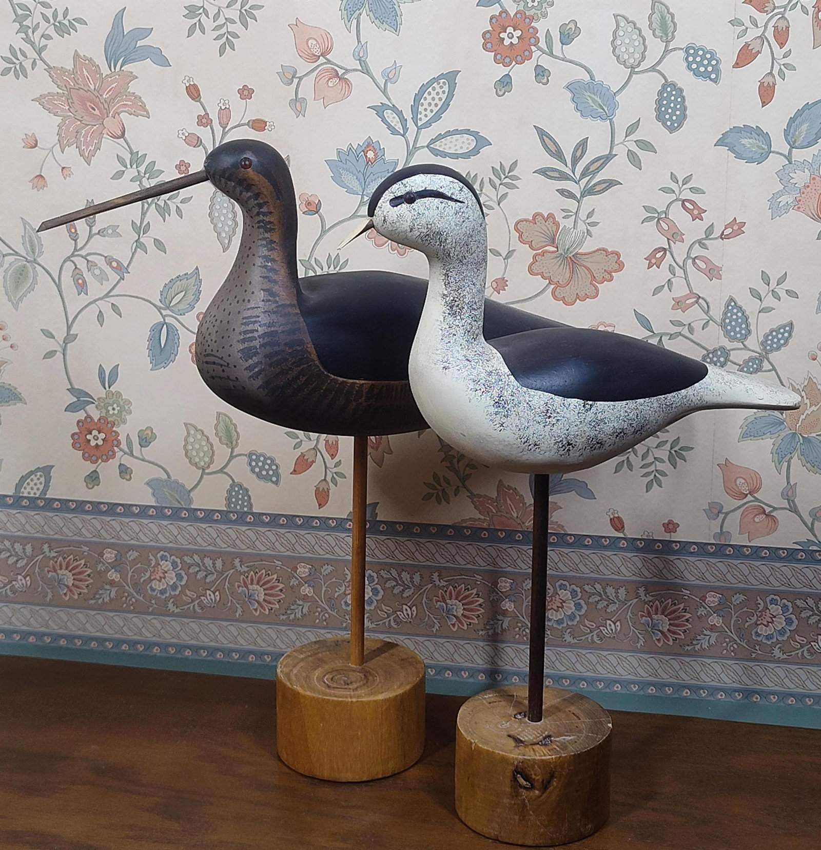 Pair Folk Art Carved & Painted Shorebird Decoys: A pair of hand-carved and hand-painted wooden shorebird decoys produced in the American folk art style. Each figure is mounted on a slender dowel support set into a circular, rough-hewn wooden base.