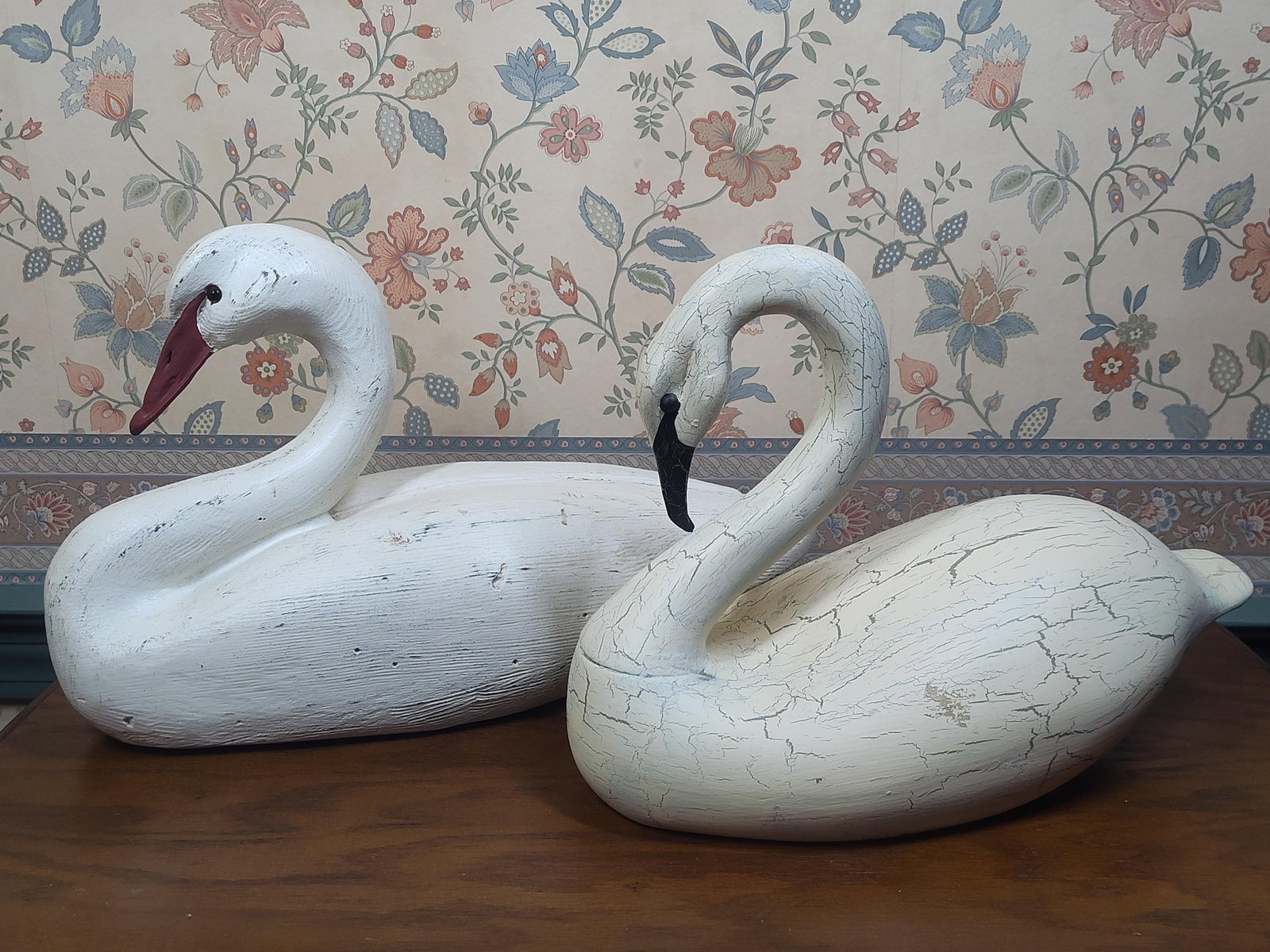 A Pair of Decorative Molded Composite Swan Decoys: A pair of decorative swan figures crafted in a folk-art style. Both pieces are constructed of a molded composite material designed to replicate the appearance of hand-carved wood. The larger swan