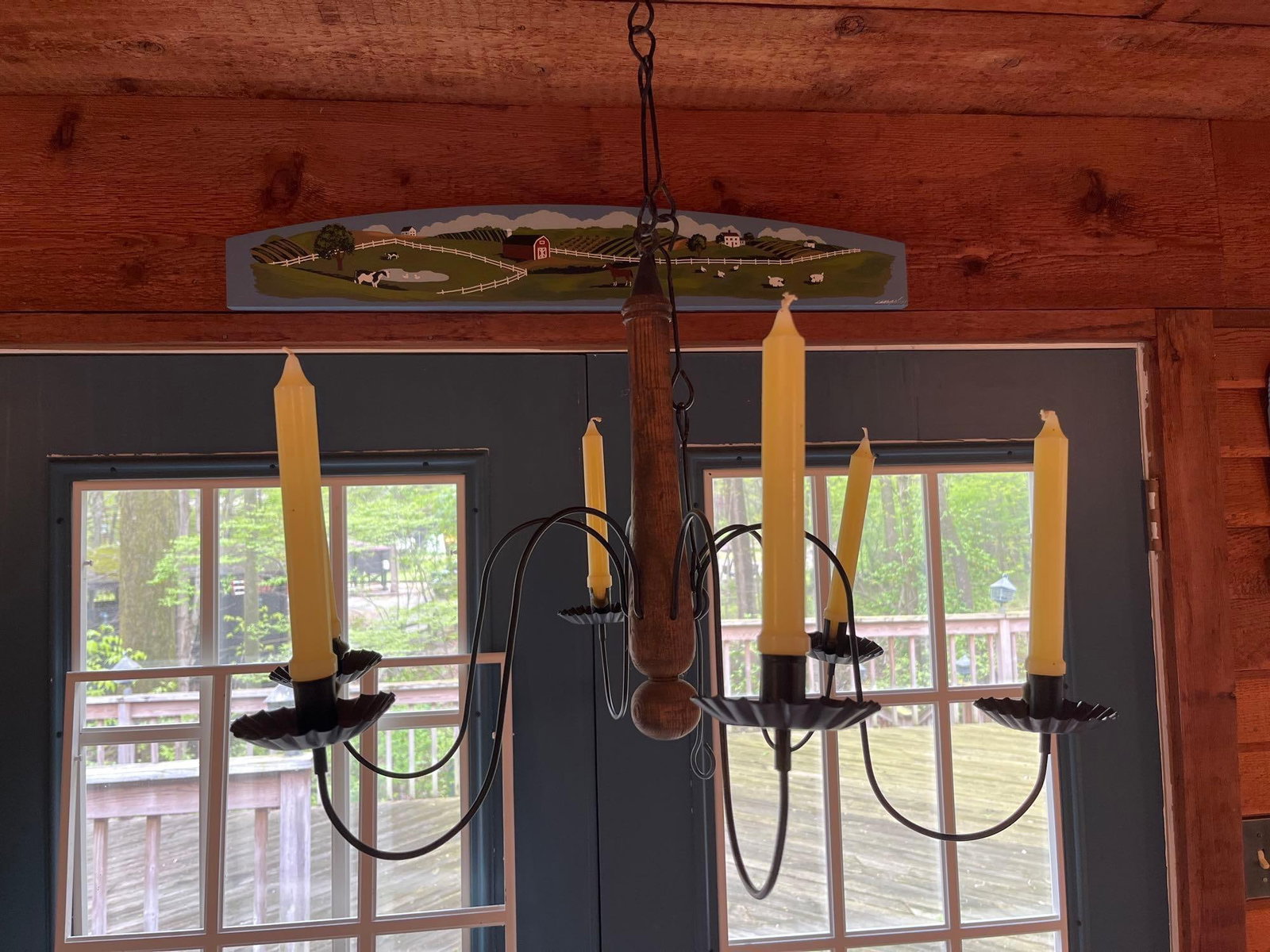 Early American Style 6-Arm Wood & Iron Chandelier: This primitive-style six-arm chandelier features a central turned wooden spindle with a dark-stained finish. Six gracefully arched wrought iron arms extend from the center, each terminating in a