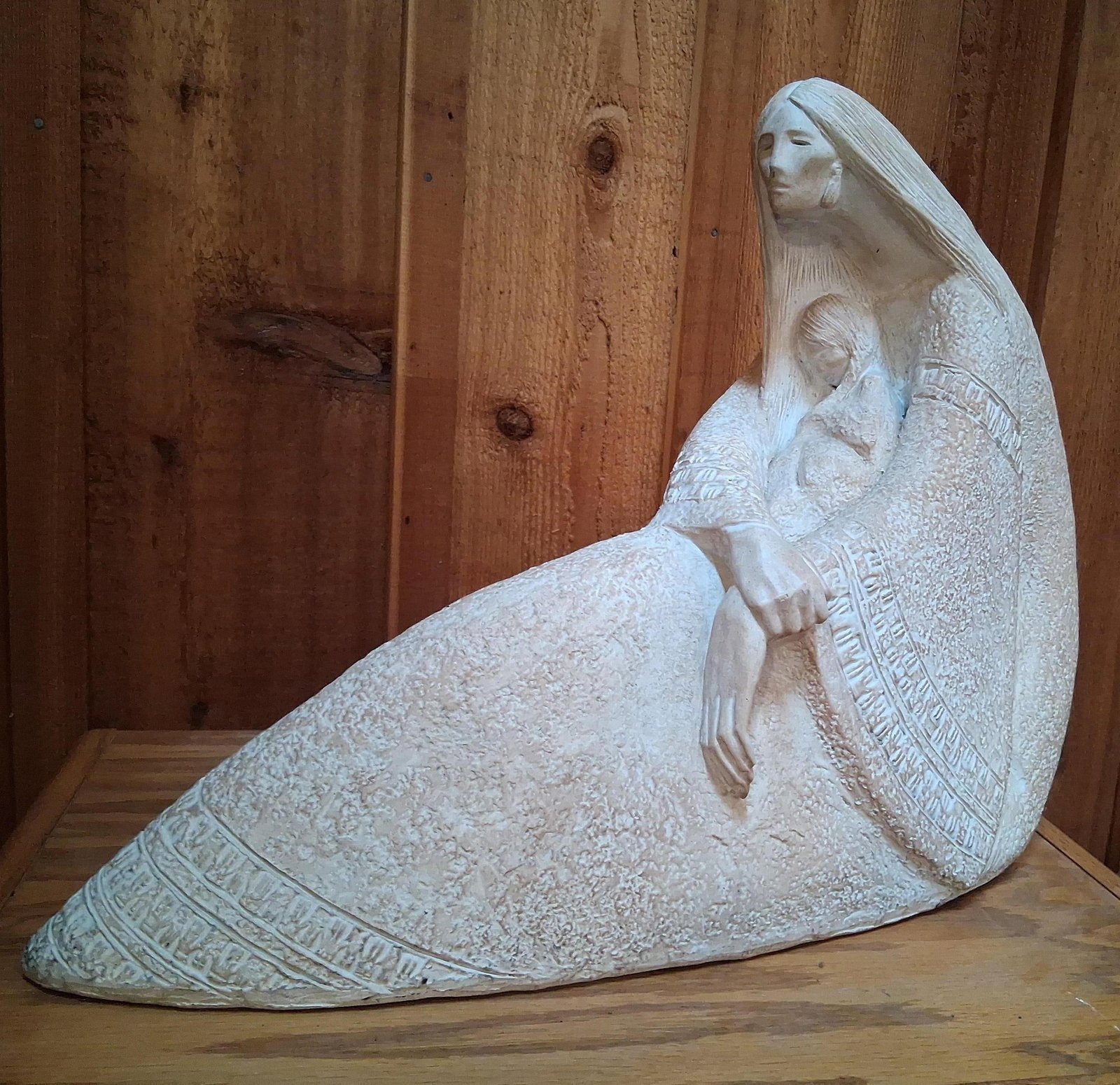 Austin Productions Acoma Mother & Child Sculpture: This cast sculpture, produced by Austin Productions as part of their Acoma series, depicts a mother and child in a stylized, protective pose. The figures exhibit elongated forms and simplified facial