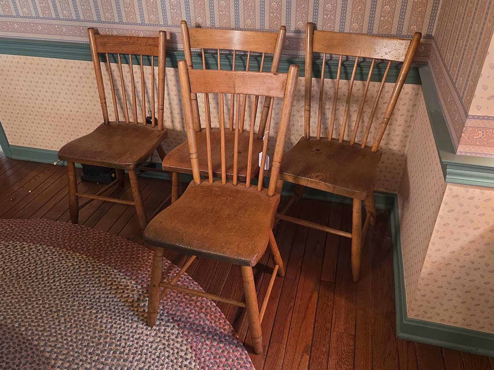 Set of Four American Step-Down Windsor Side Chairs: A set of four side chairs in the American Windsor style, specifically the step-down variety. The chairs are constructed of mixed woods, featuring sculpted solid plank seats and notched or stepped ends