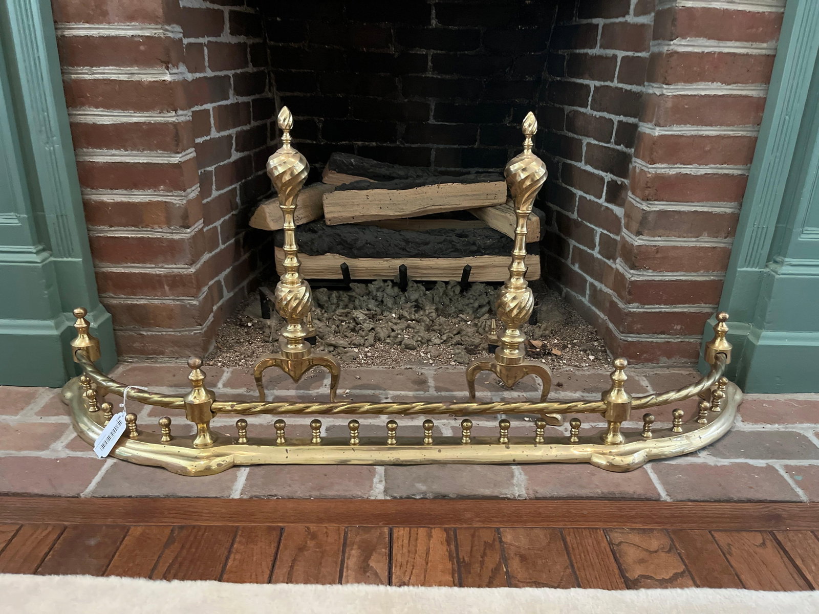 Set Colonial Revival Brass Fireplace Accessories: This set of Colonial Revival style fireplace accessories includes a matching pair of andirons and a coordinating bowed hearth fender, all crafted from polished brass and dating to the 20th century.