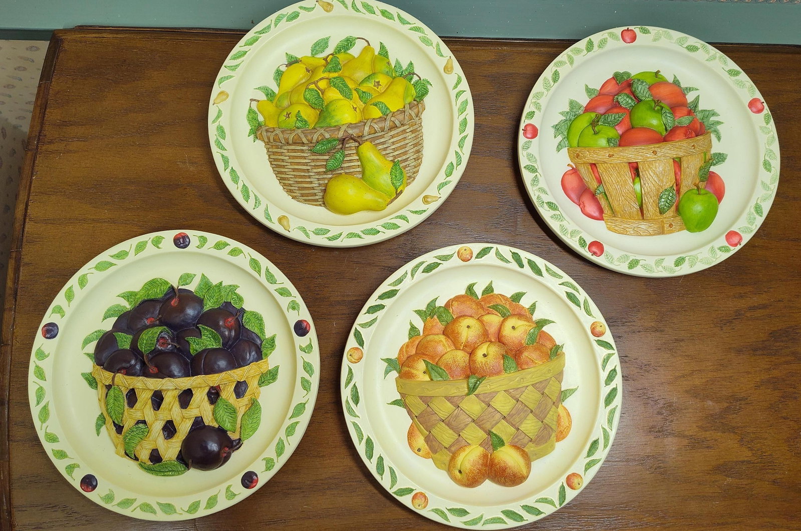 Set 4 Kathleen O'Malley Harvest Ceramic Plates: A set of four hand-cast and hand-painted relief ceramic decorative wall plates from the Bountiful Harvest collection, produced by Rhodes Studios. Designed by artist Kathleen O'Malley and copyrighted