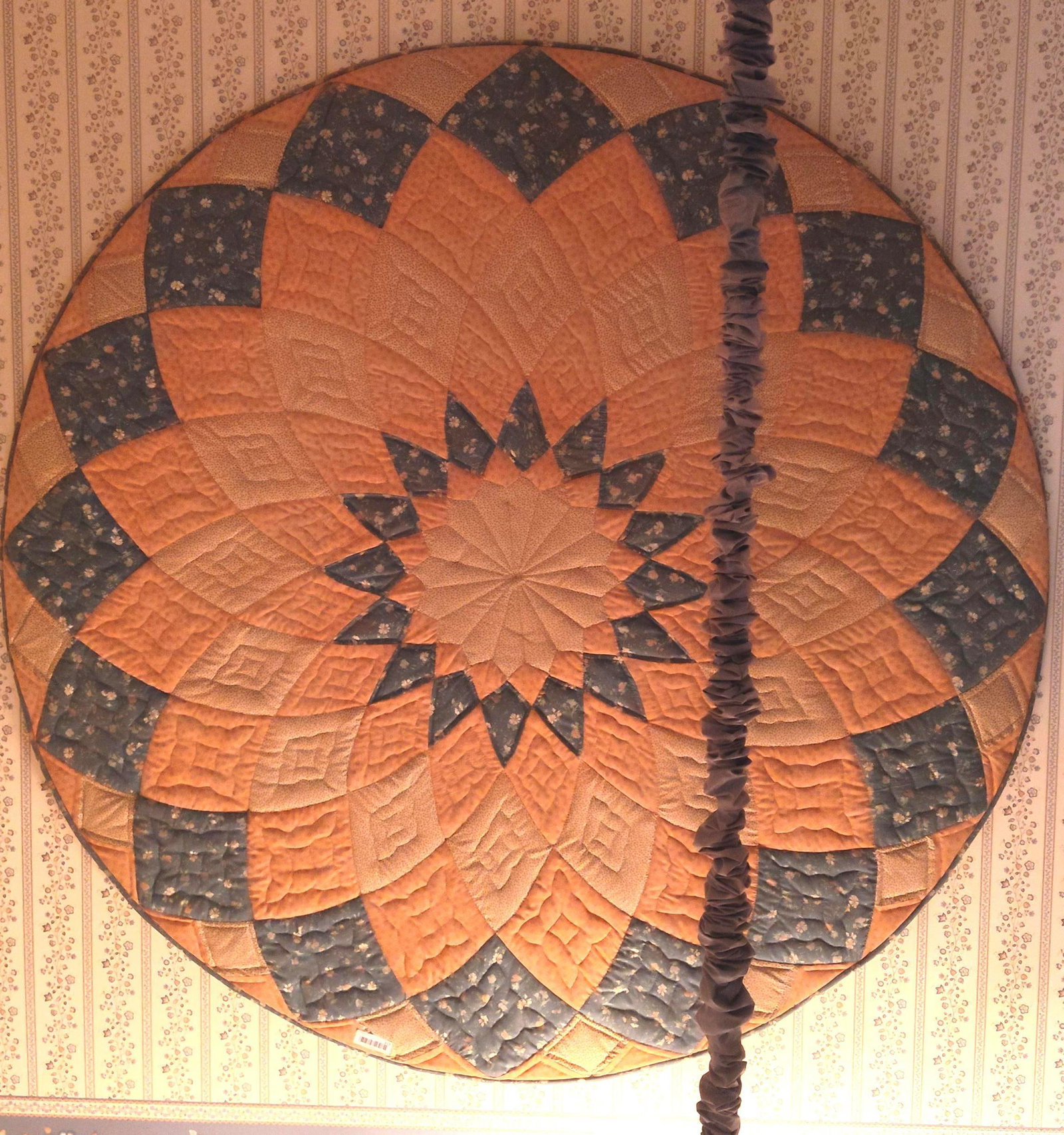 Circular Dahlia Quilted Wall Hanging, Earth Tones: Approx 71 inches diameter. Mounted to board. A circular quilted textile, likely intended as a wall hanging or table topper, featuring the Giant Dahlia pattern. The construction consists of pieced