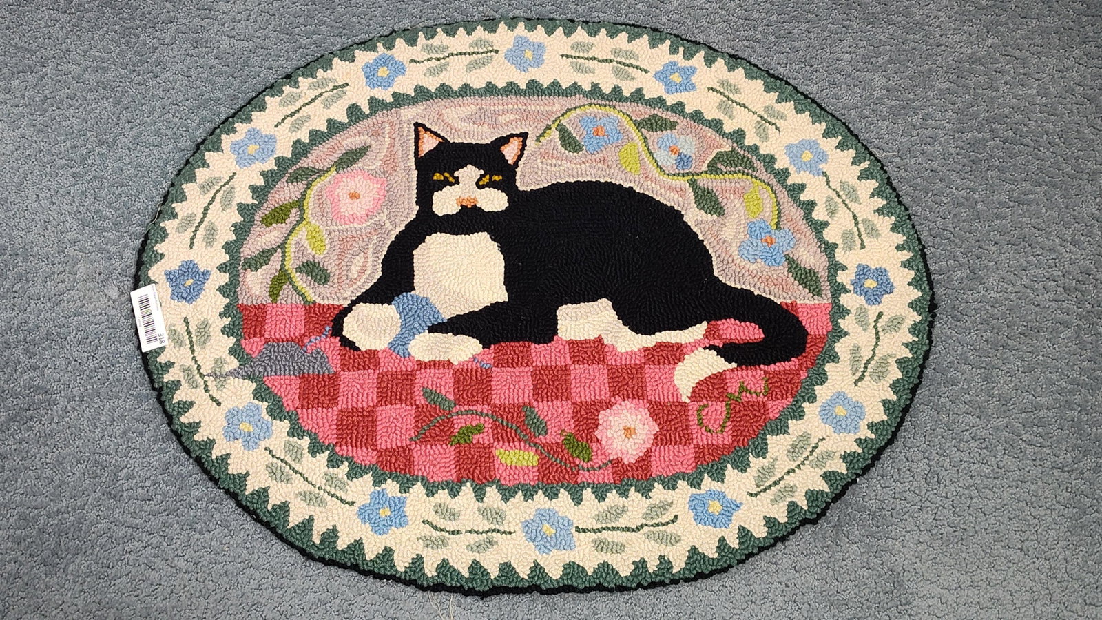 Claire Murray Country Cat Hand-Hooked Wool Rug: This oval hand-hooked wool rug, designed for Claire Murray and titled Country Cat, features a folk-art-style composition. The central motif depicts a black and white tuxedo cat reclining on a red and 