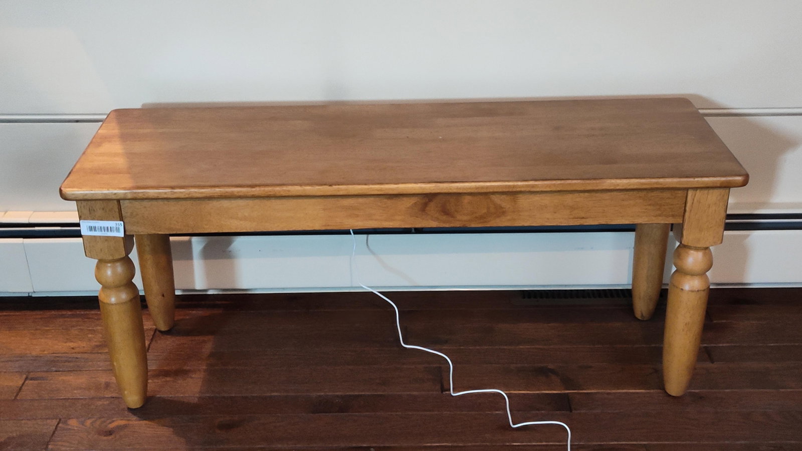 Country Style Turned Leg Stained Wood Bench: This wooden bench features a solid rectangular top with rounded edges and corners. The top sits on a simple apron supported by four turned hardwood legs. Each leg is designed with a square block