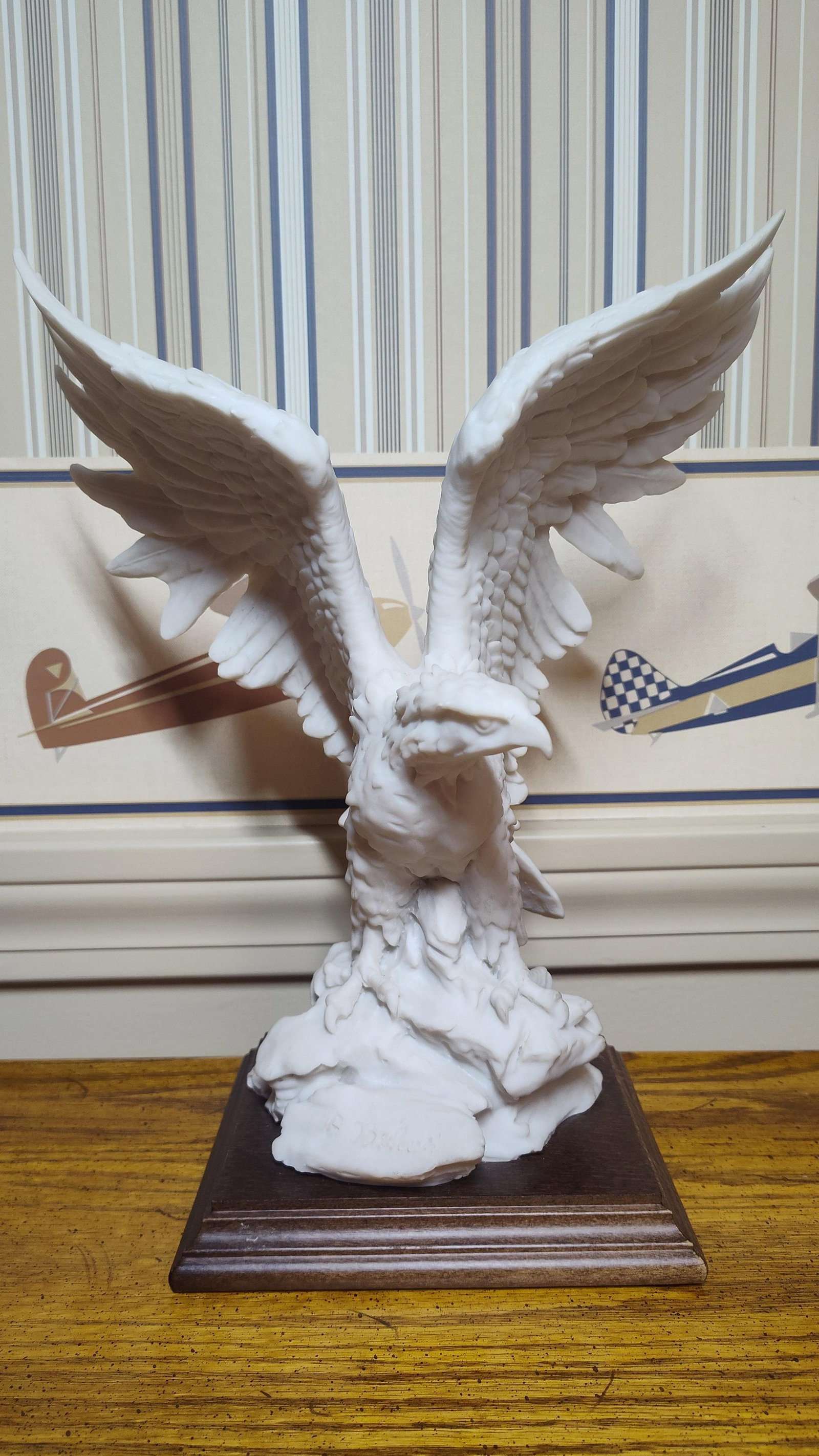 A. Belcari Capodimonte Style Eagle Sculpture: This Italian sculpture depicts an eagle with outspread wings in a landing or takeoff posture, perched atop a rocky base. Designed by artist A. Belcari, the piece is crafted from a matte white