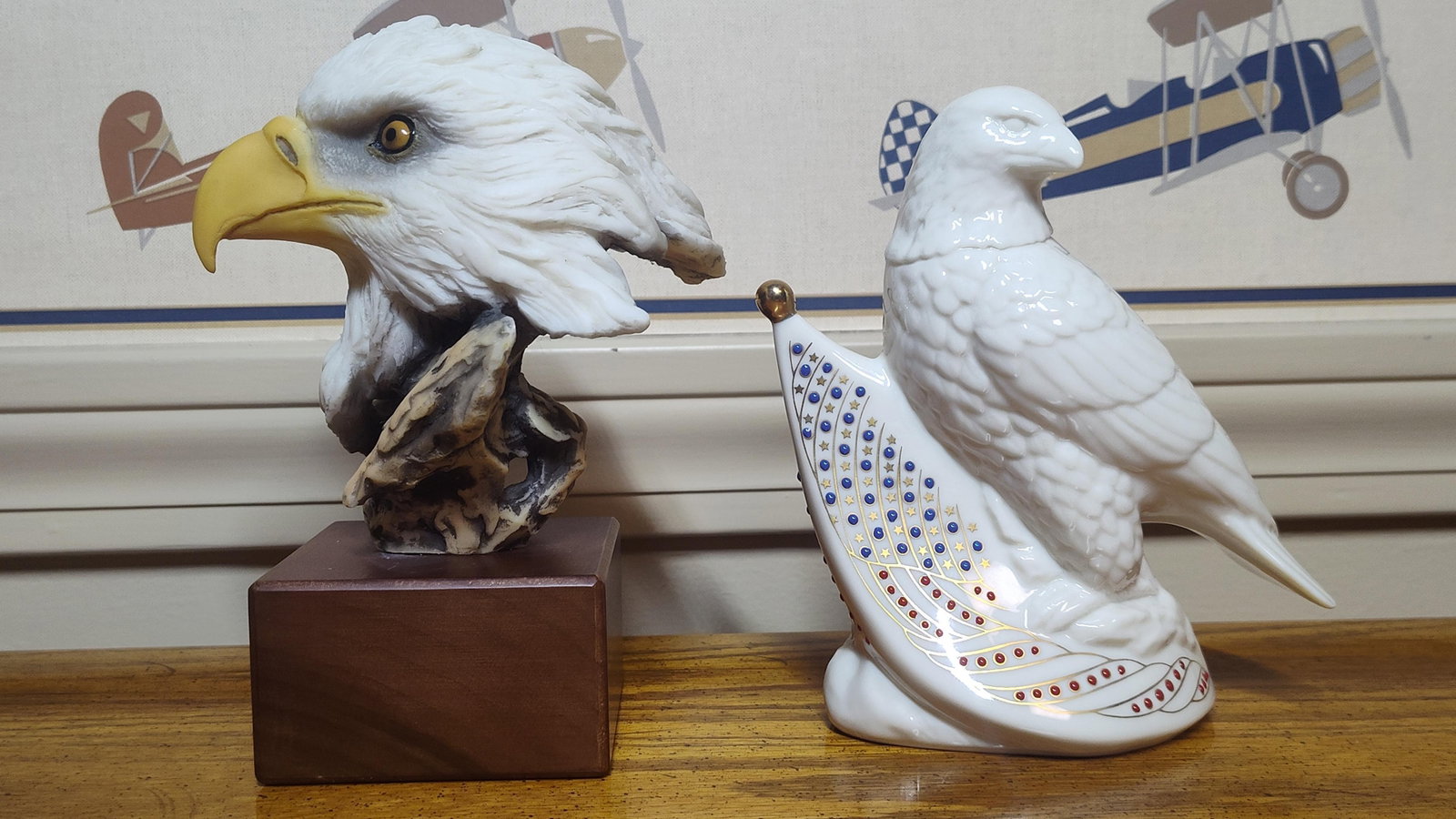 Composite Eagle Bust & Jeweled Porc. Sculpture: This lot features two eagle-themed decorative objects of varying materials and styles. The first item is a realistic bald eagle bust mounted on a square wooden plinth. This piece, titled Above