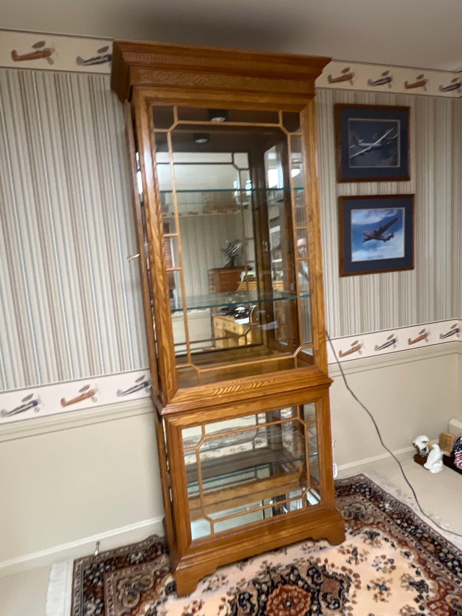 Attributed to Pulaski Lighted Oak Curio Cabinet: 82x 29x 39.5. A two-piece lighted curio cabinet constructed of oak solids and veneers with a medium-brown finish, attributed to Pulaski Furniture Corporation. The cabinet features a traditional design