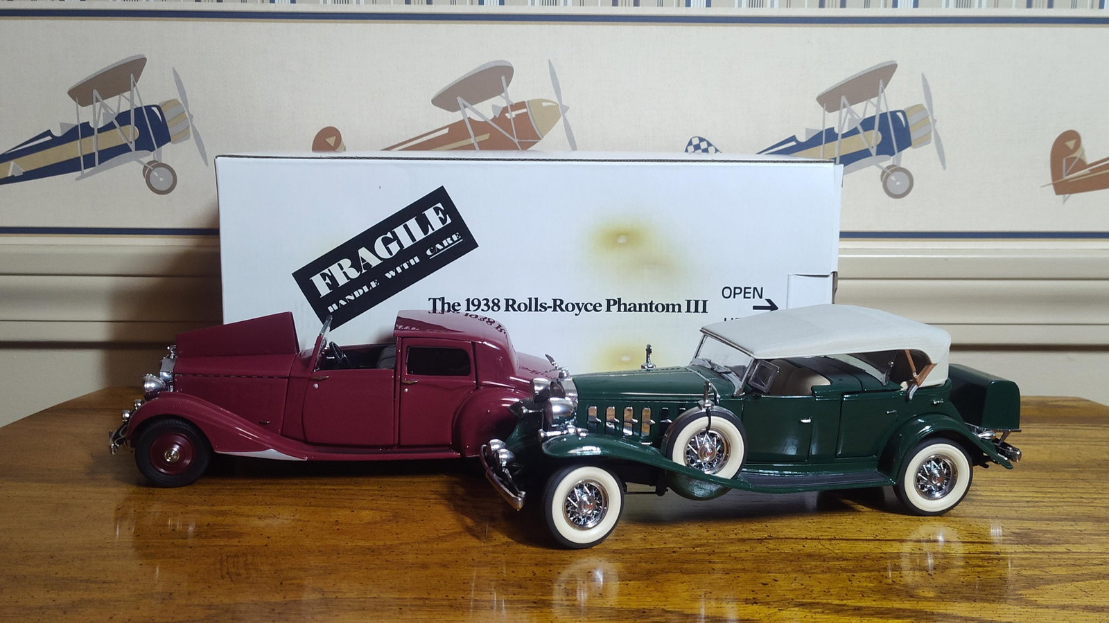 Pair: Rolls-Royce & Cadillac Model Cars: A pair of precision-engineered model automobiles, likely produced by Franklin Mint. The first model is a 1938 Rolls-Royce Phantom III finished in burgundy with a black interior. This right-hand drive