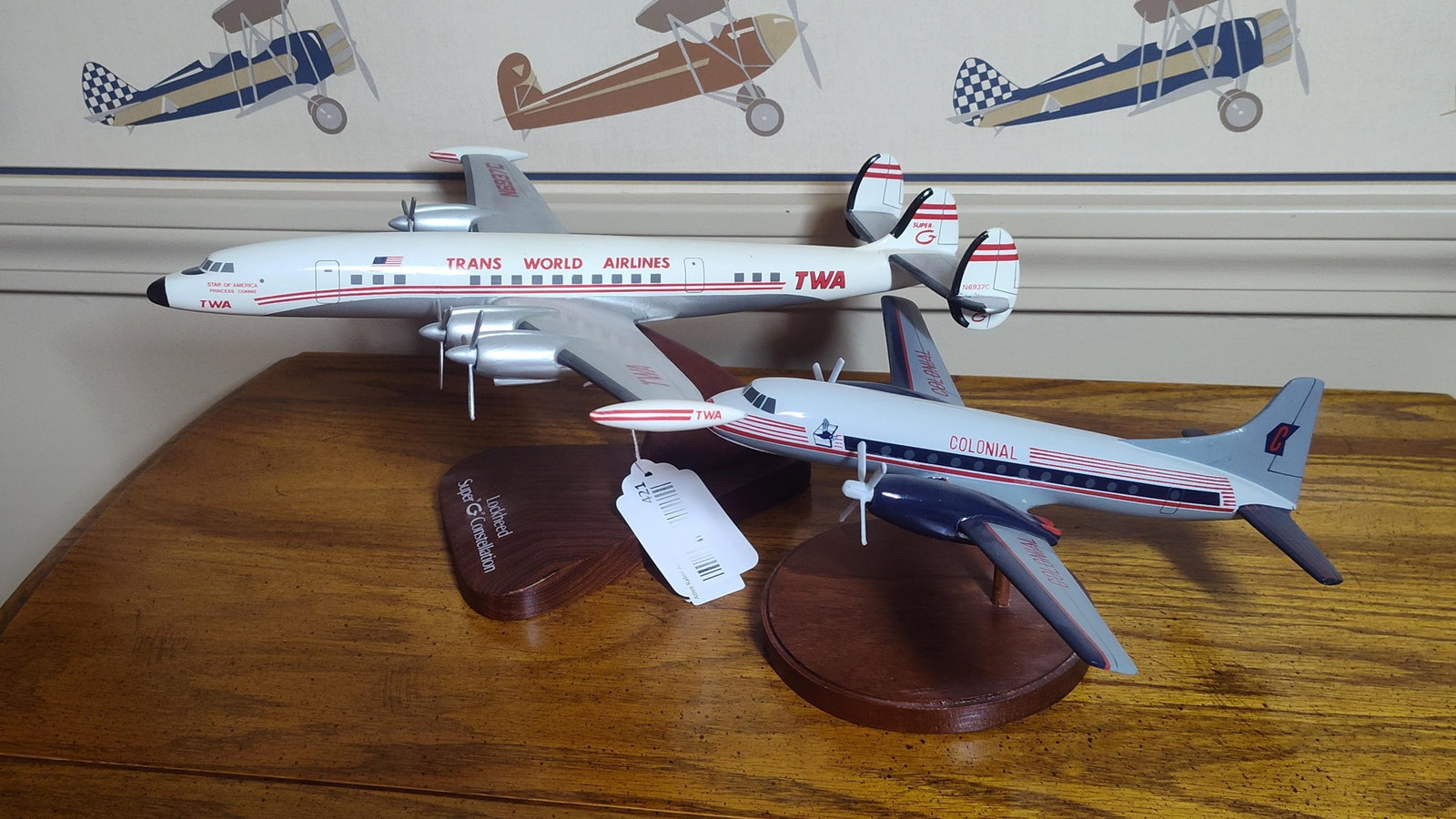 Pair Scalecraft Wood Model Airliners: TWA/Colonial: This lot features two hand-painted wooden aircraft display models, identified as Scalecraft productions, each mounted on a mahogany-style wooden base. The first model represents a Lockheed L-1049G Sup