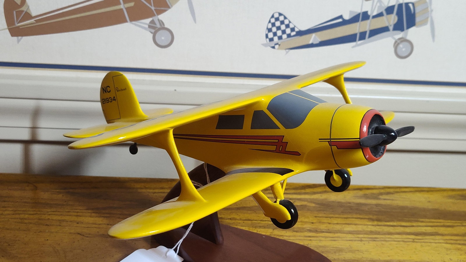 Beechcraft Model 17 Staggerwing Desktop Model: A contemporary desktop display model of the Beechcraft Model 17 Staggerwing biplane. The aircraft is constructed from carved wood or composite material and finished in a high-gloss yellow paint scheme