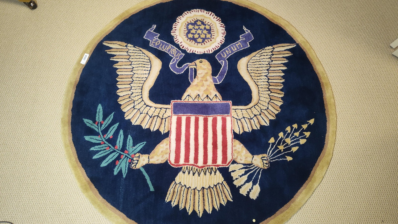 Hand-Tufted Great Seal of the United States Rug: 59 inches round. A round, hand-tufted wool pile rug featuring the Great Seal of the United States. The central design depicts a bald eagle with outspread wings. On its breast is a shield with red and 