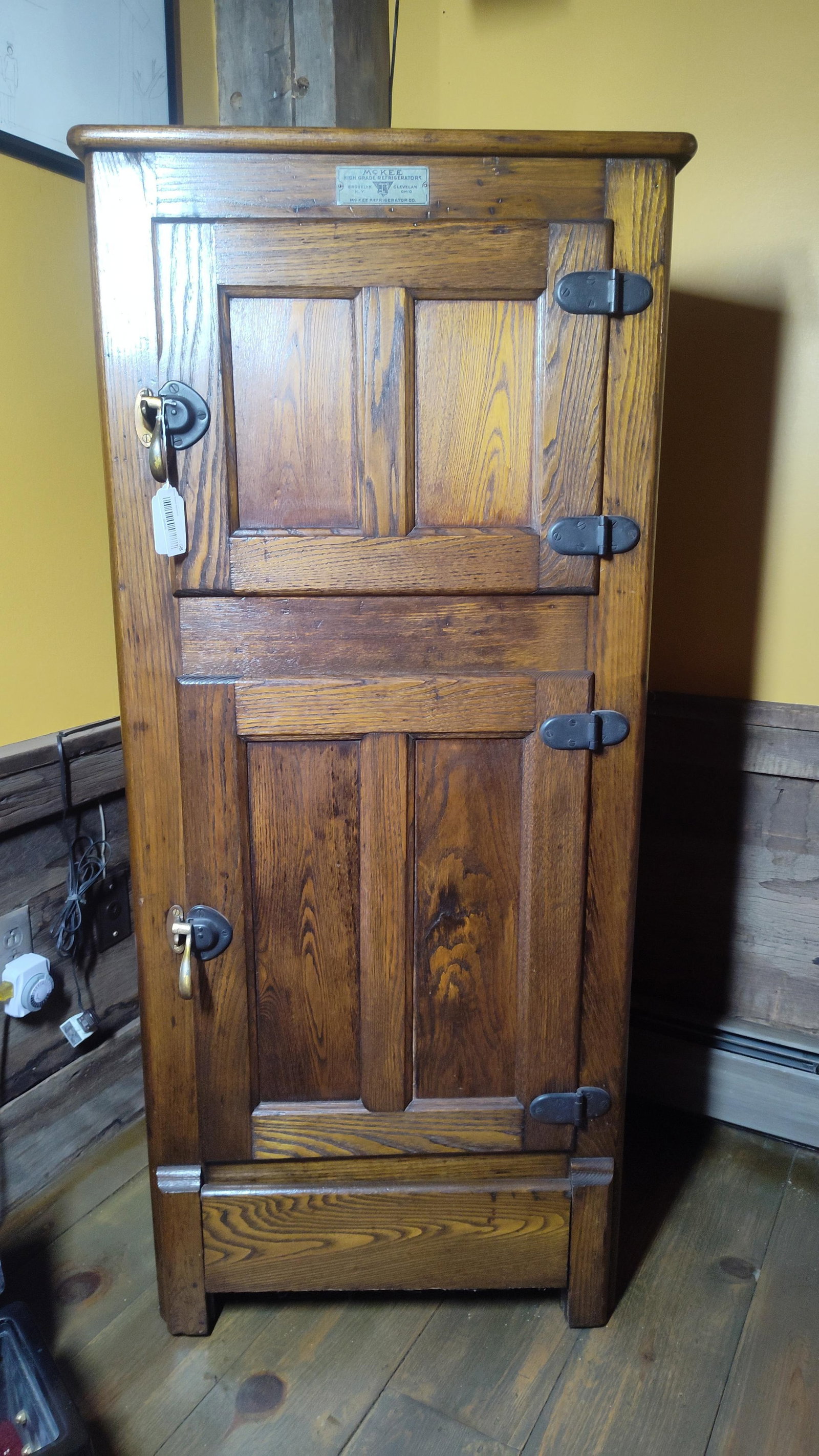 Antique McKee Refrigerator Co. Two-Door Oak Icebox: This antique two-door icebox was manufactured by the McKee Refrigerator Company, as confirmed by the original metal plaque affixed to the upper front rail. The cabinet is a single-piece construction m