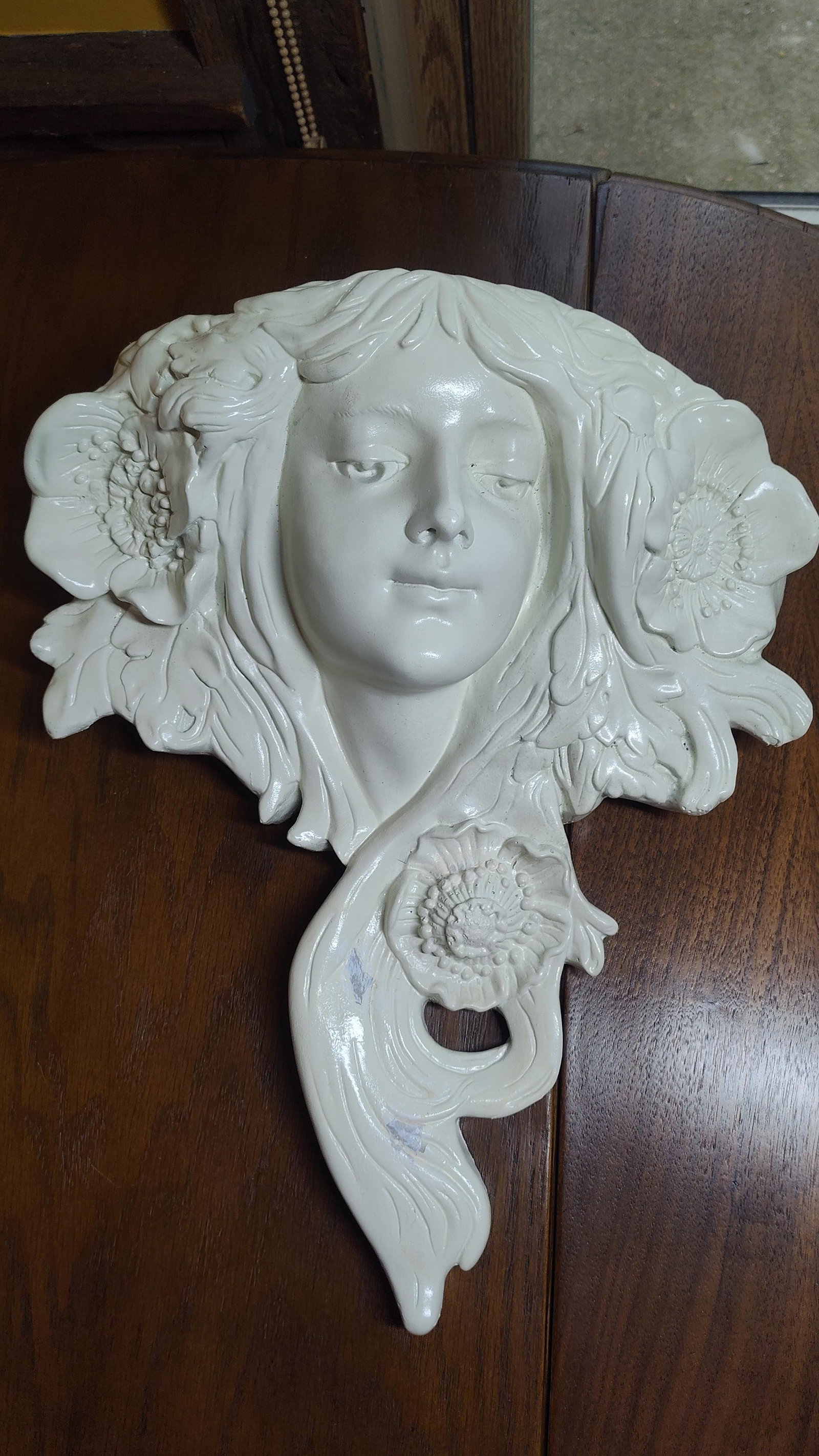 Creative Products Art Nouveau Poppy Maiden Mask: Cast composition wall sculpture in the Art Nouveau style, depicting an idealized female face in high relief. The figure is characterized by a serene expression and downcast eyes, surrounded by