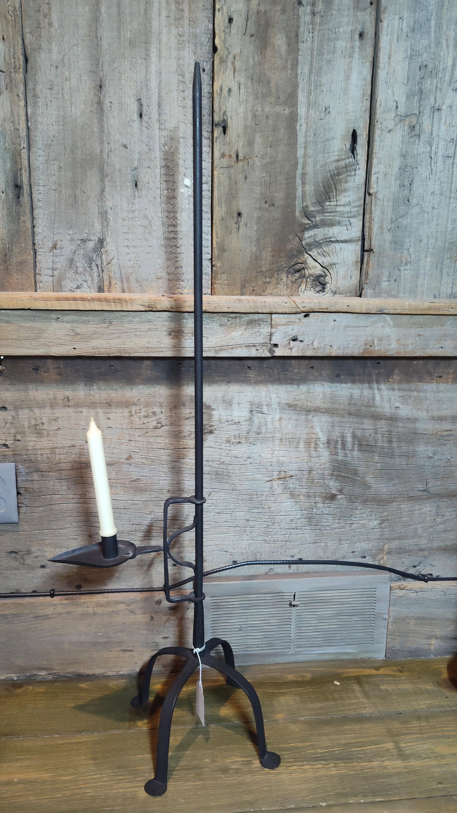 Colonial Wrought Iron Ratchet Floor Candle Stand: This height-adjustable floor candle stand is constructed of hand-forged wrought iron with a matte black finish. The design follows an Early American or Colonial pattern, featuring a tripod base with