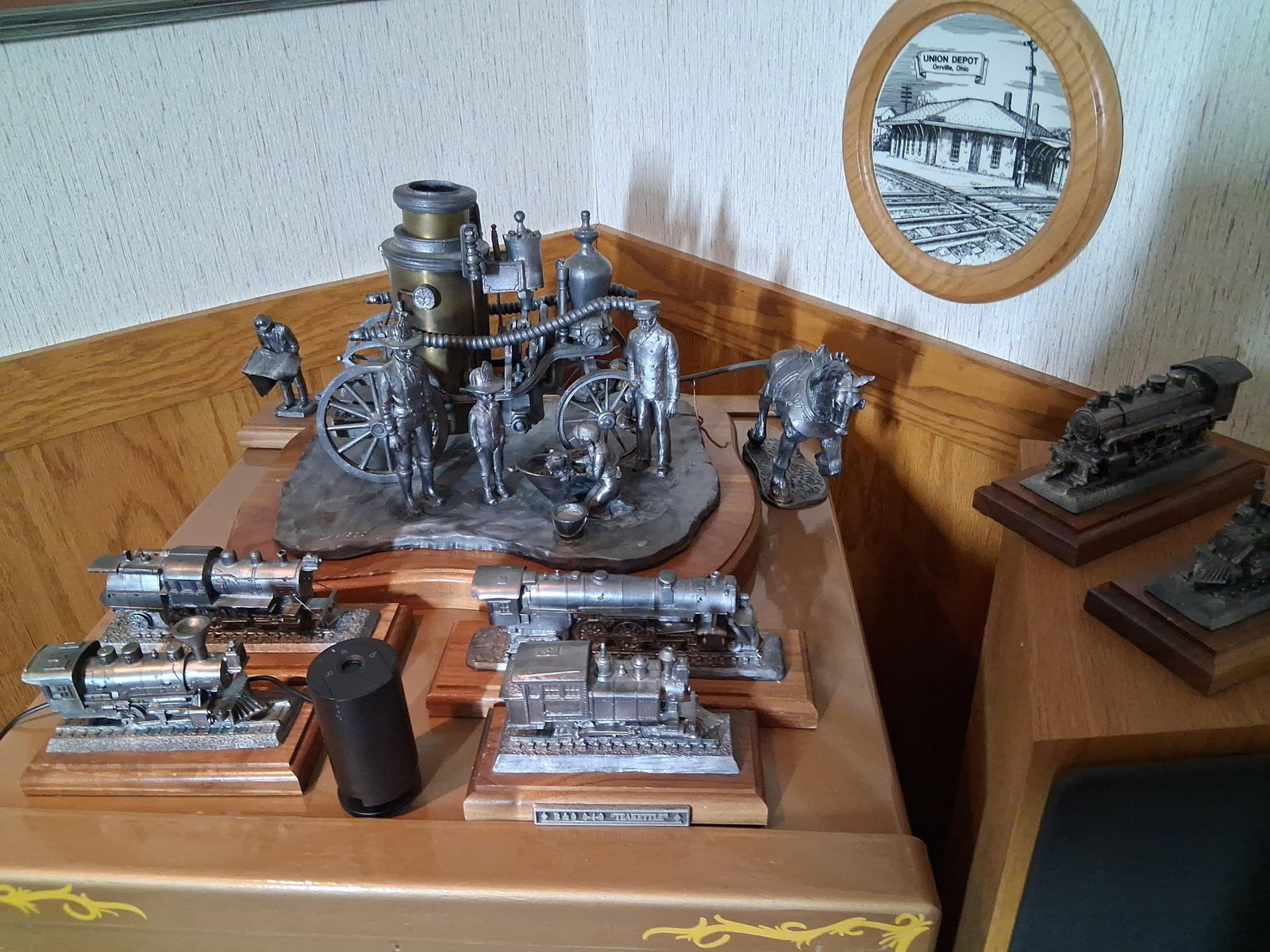 Michael Ricker Pewter Steam Transport Sculptures: This lot features a collection of solid cast pewter sculptures by Michael Ricker, centered on the theme of historical steam-powered transportation. The primary piece is a multi-figure scene depicting 