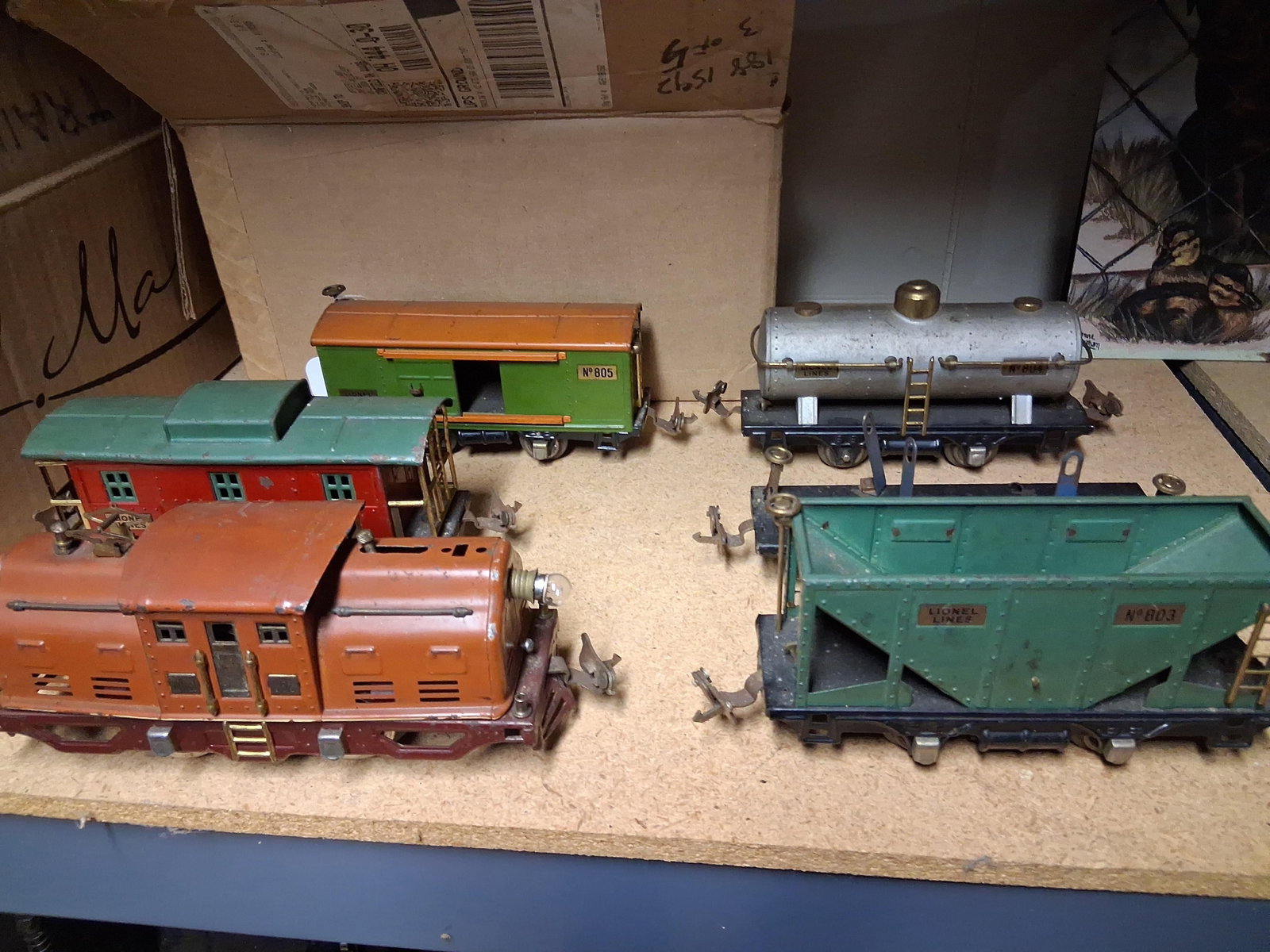 Lionel Pre-War O-Gauge Tinplate Model Trains: This collection of vintage pre-war O-gauge model train items is manufactured by Lionel. The set consists of an electric-style locomotive, five pieces of rolling stock, and a quantity of three-rail tra