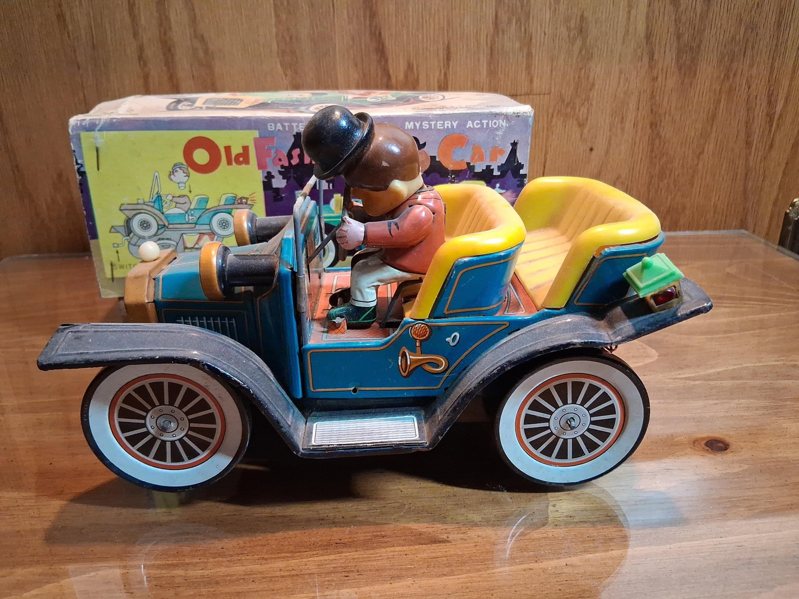 Nomura (TN) Battery-Operated Tin Car w/ Box: This is a vintage battery-operated toy car manufactured by the Nomura Toy Company (TN) of Japan. The model, identified as the Old Fashioned Car, is constructed primarily of lithographed tinplate with 