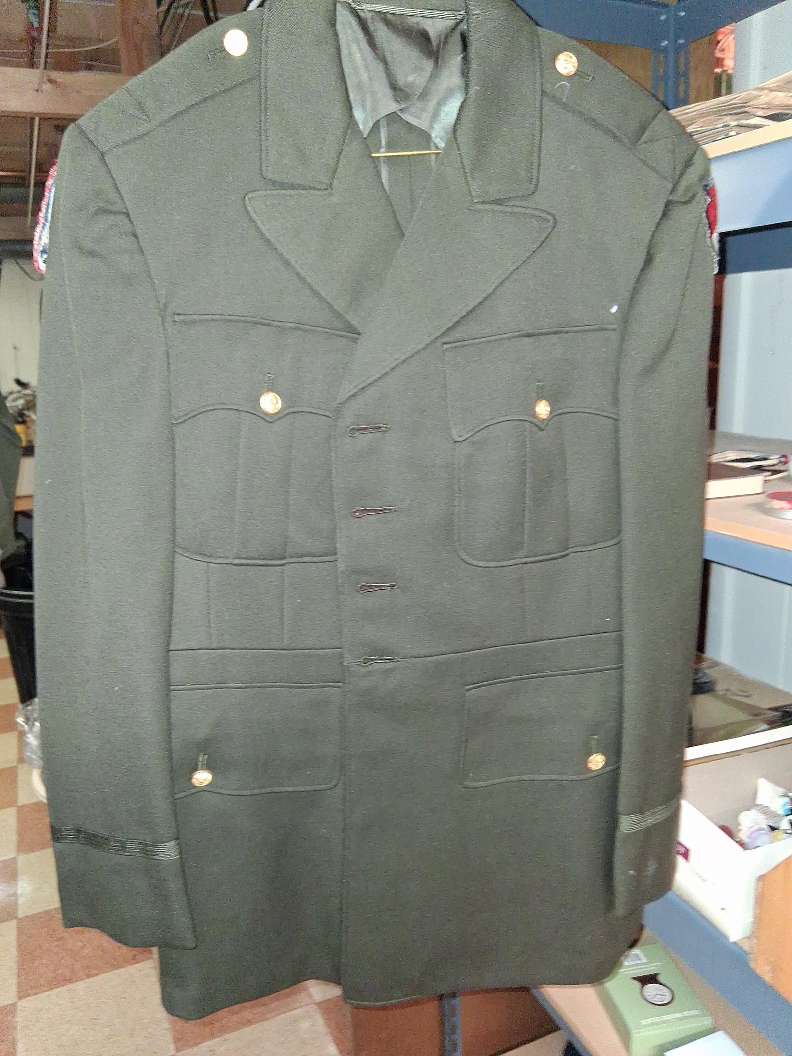 US Army Officer Coat w/ USAREUR & Log. Patches: This US Army officer service coat is the Army Green Shade 44 (AG-44) pattern, constructed from heavyweight green wool or a wool-blend fabric. The garment features a four-button front closure, four