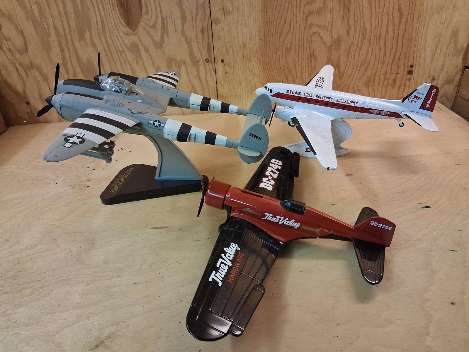 3 Model Planes: Atlas Tires DC-3 & True Value Bank: This collection features three model airplanes, including two advertising promotional items and one military scale model. The first item is a Lockheed P-38 Lightning scale model constructed of plastic
