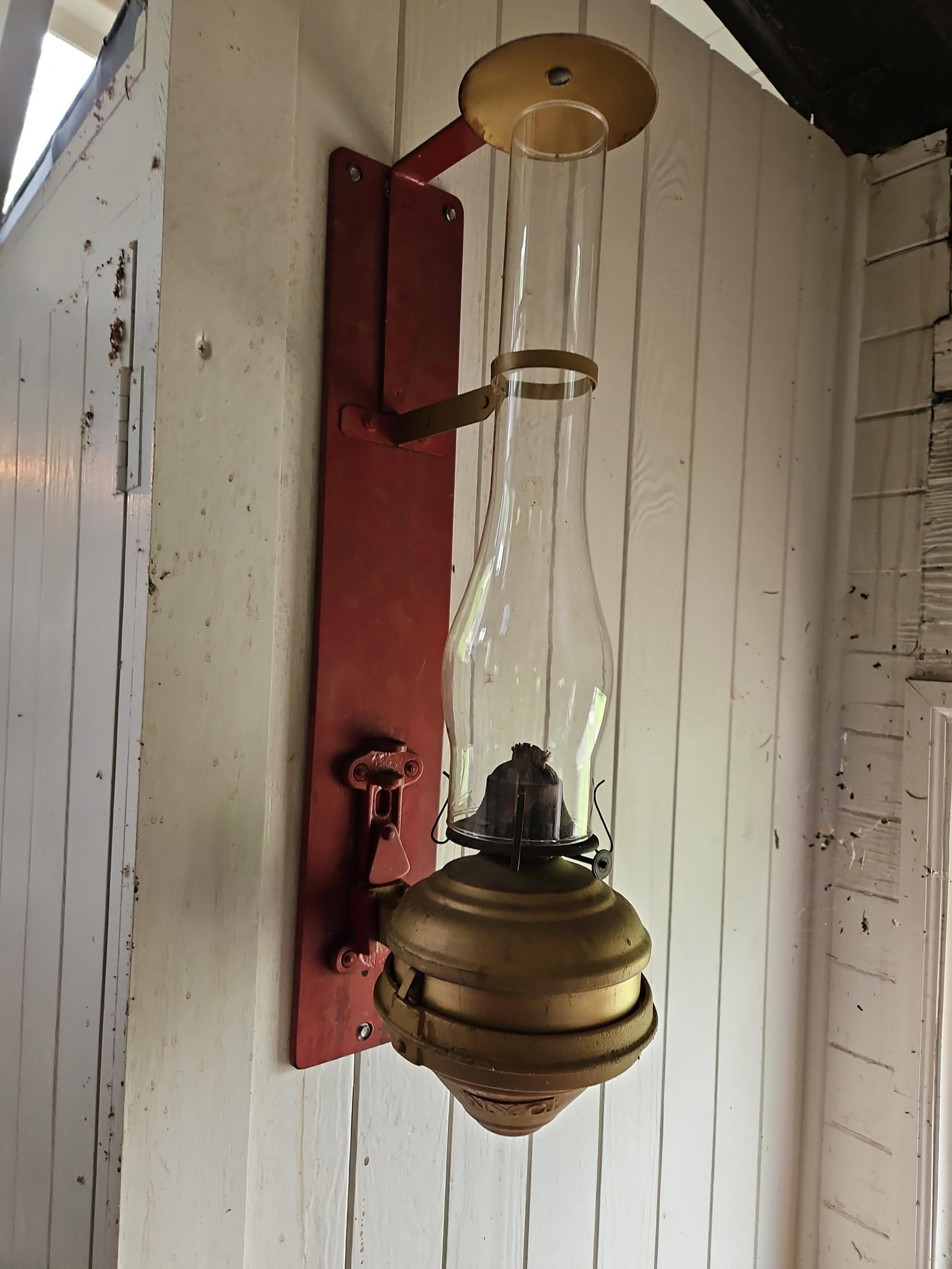 New York Central Railroad Caboose Wall Oil Lamp: This antique wall-mounted oil lamp is a piece of railroadiana designed for use in a caboose or railway car interior. The assembly features a bulbous, stepped brass font that tapers to a point at the b