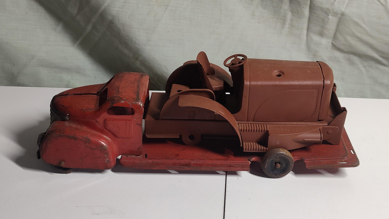 Pair Lincoln Toys Canada Pressed Steel Toys: This lot features two vintage pressed steel toys attributed to Lincoln Toys of Canada, dating to the mid-20th century. The first item is a cab-over-engine (COE) transport truck finished in red with an