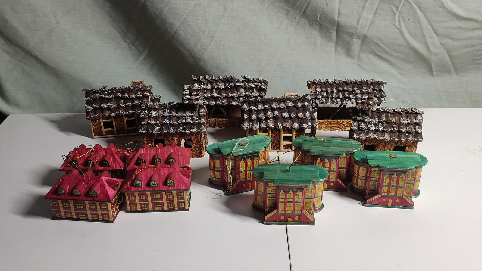 Set 12 Natural Fiber & Pinecone Buildings: This collection of twelve miniature decorative buildings consists of two distinct styles of hand-crafted structures. Six of the buildings are rustic cottages featuring roofs constructed from