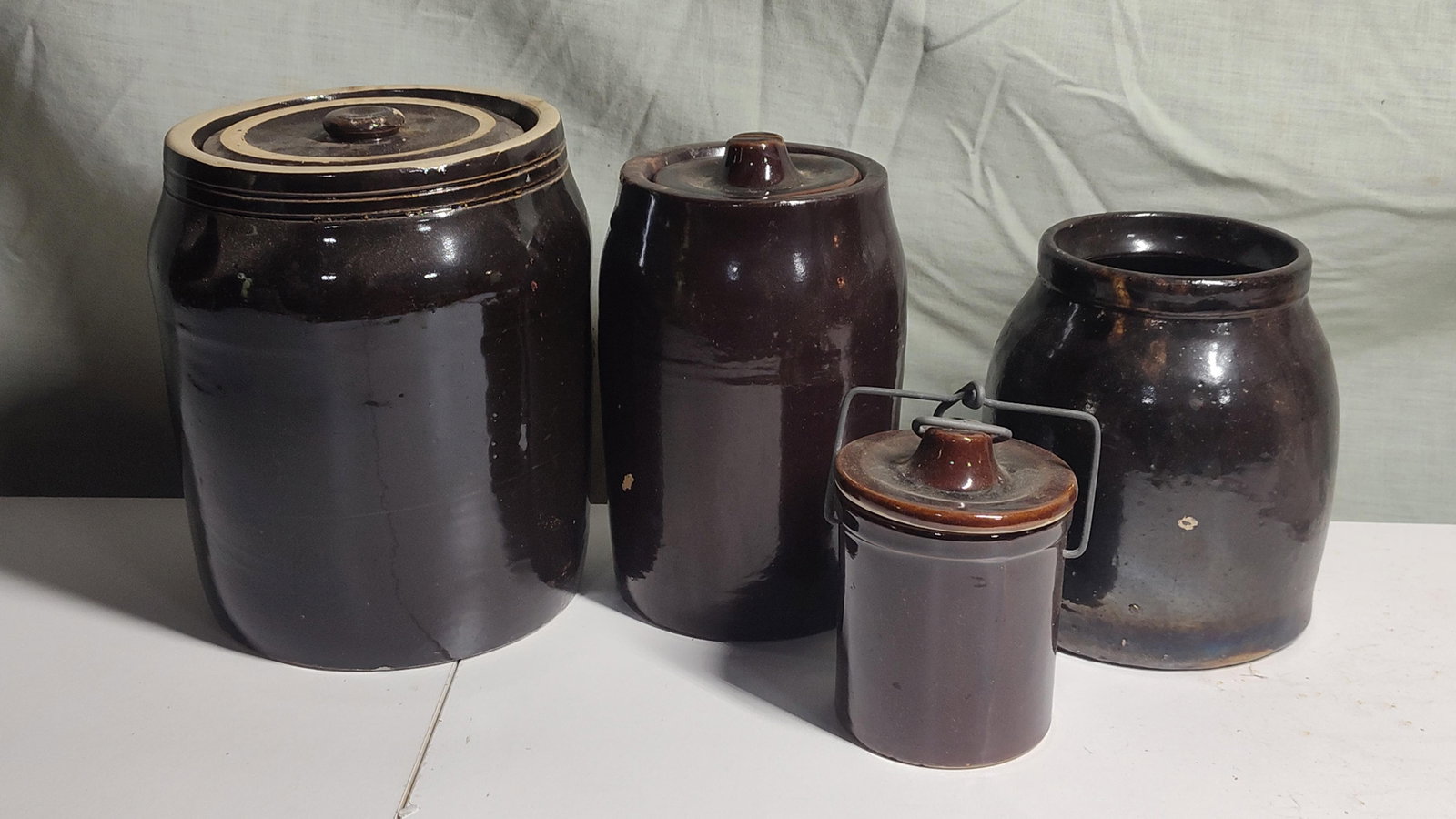 American Albany Slip Glazed Stoneware Vessels: This collection consists of several pieces of American utilitarian stoneware produced during the late 19th to early 20th century. All vessels are finished with a dark brown Albany-type slip glaze, a