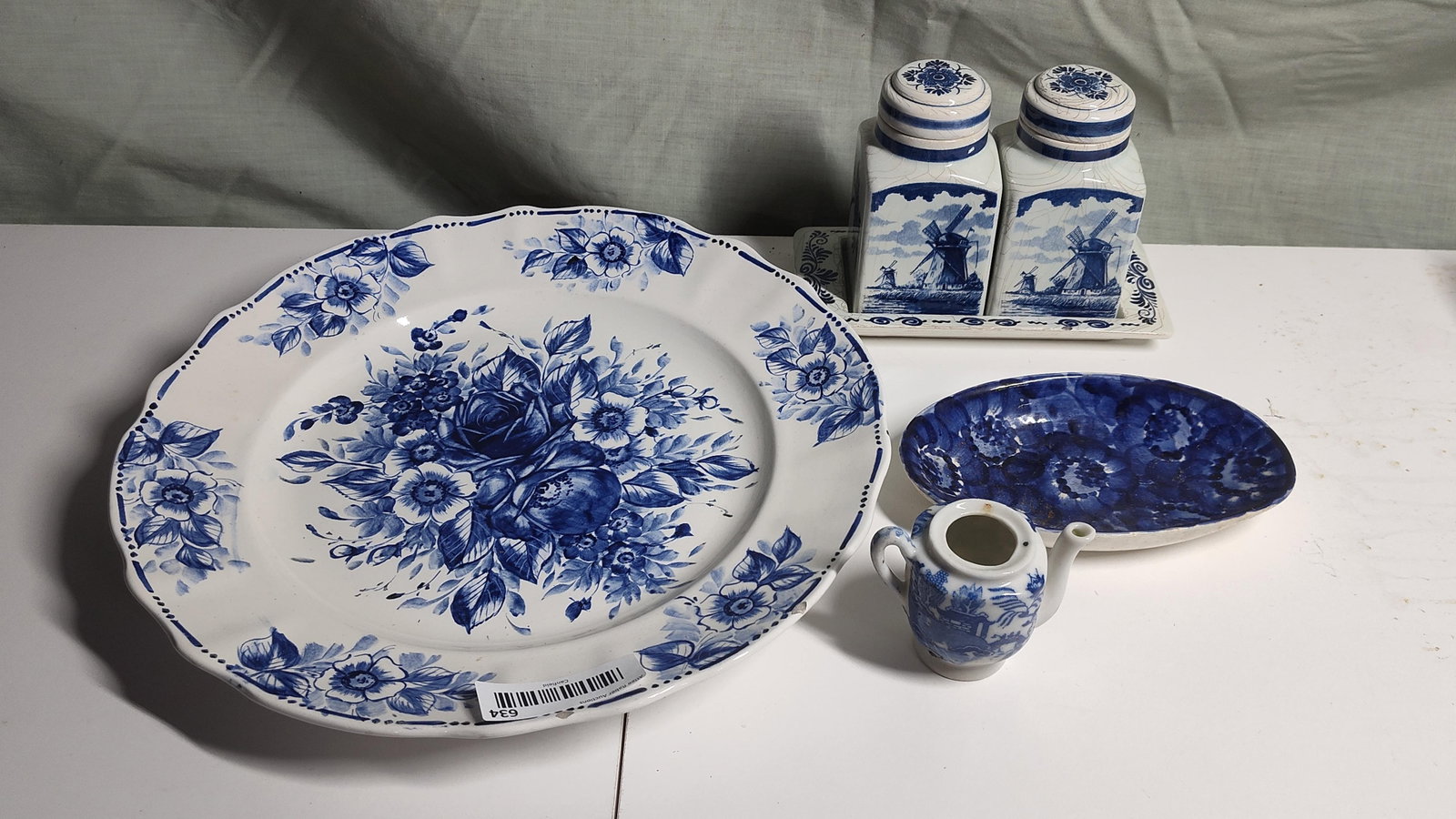 An Assortment of Blue and White Ceramic Tableware: An assortment of ceramic items featuring various blue and white decorative techniques. The collection includes a large circular platter with a scalloped rim, decorated with hand-painted cobalt blue