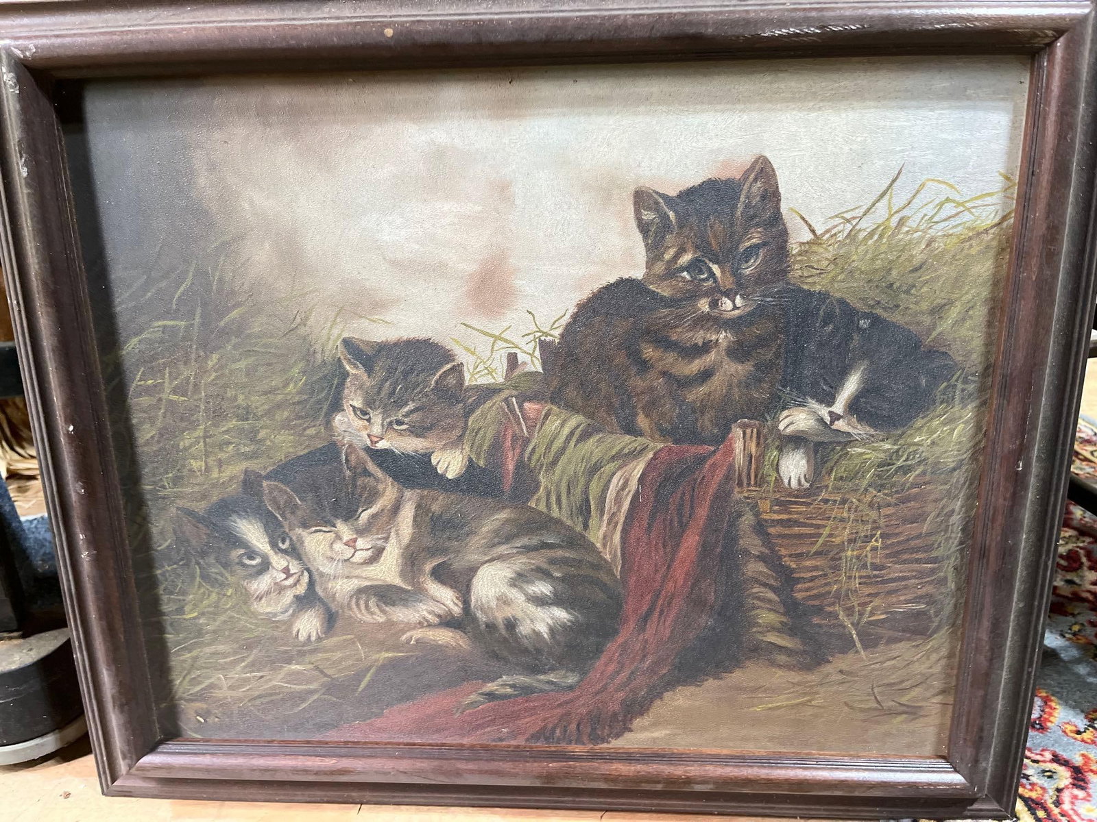 Victorian Style Kittens in a Basket Oleograph: This vintage oleograph depicts a sentimental animal genre scene in the late 19th to early 20th-century style. The composition features four kittens with tabby and bicolor markings nestled together in