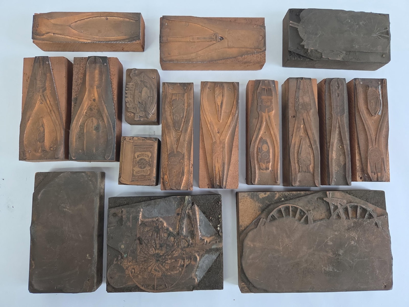 Collection of 14 Industrial and Agricultural Letterpress Printing Blocks: This collection contains 14 letterpress printing blocks constructed from etched metal plates mounted to wooden bases. The subject matter predominantly features industrial hand tools and agricultural m
