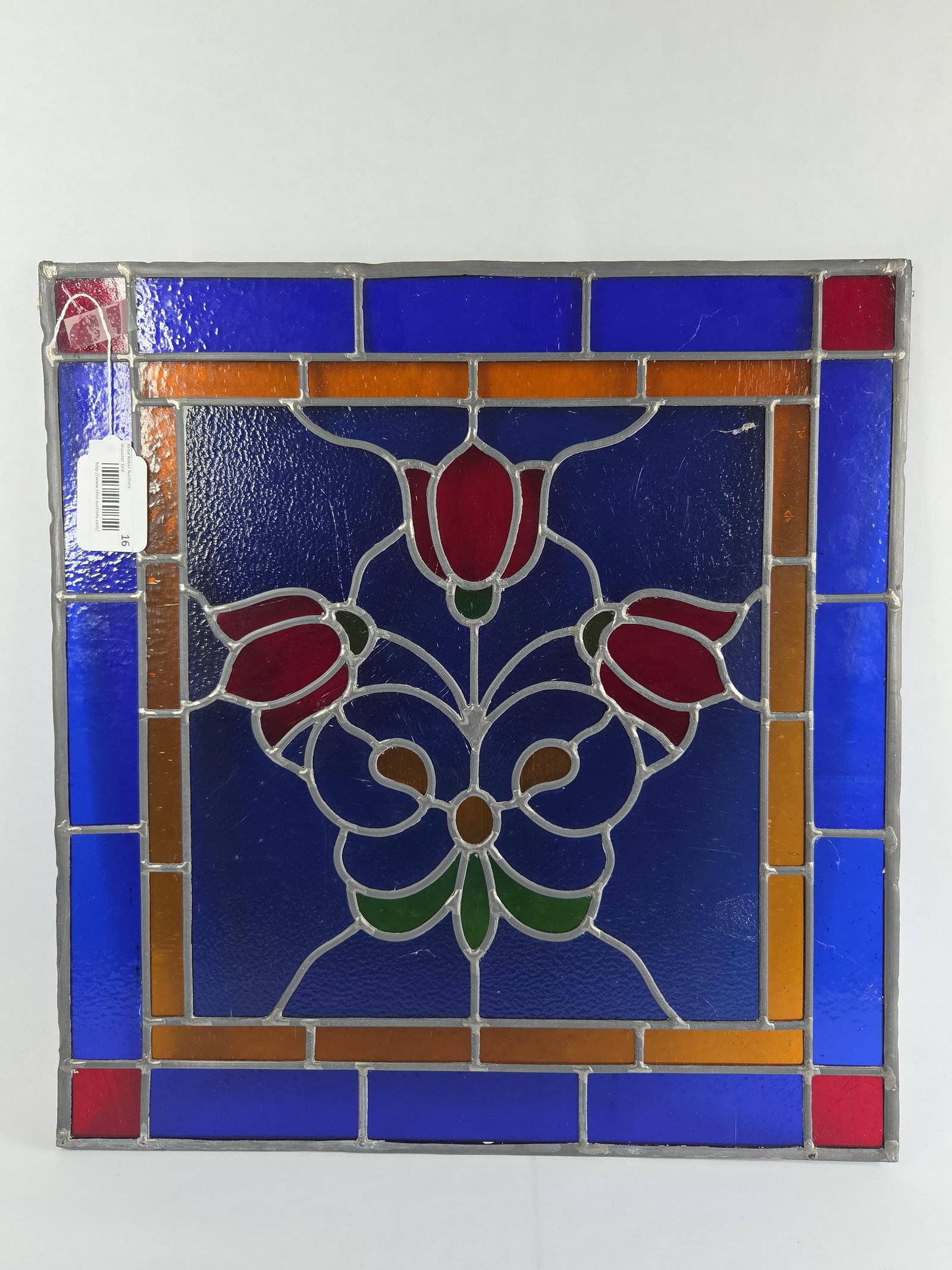 Signed Diamond Jims Lead Stained Glass Panel with Tulip Motif: A leaded stained glass panel featuring a central stylized floral motif designed by artist Donald Simpson. The central composition consists of three red tulip-like blossoms with green bases, arranged