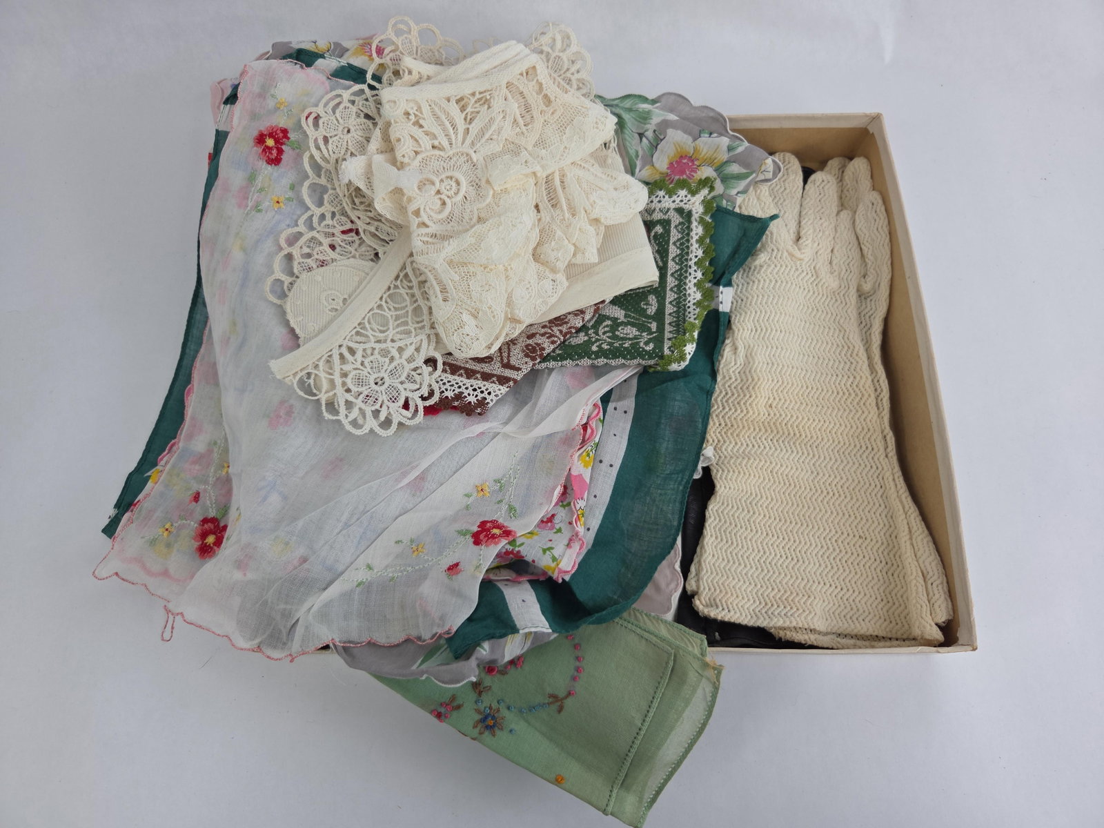 A Collection of Ladies' Accessories Including Handkerchiefs, Gloves, and Lace Trimmings: An assortment of mid-20th century ladies' fashion accessories featuring a variety of textiles and materials. The collection includes multiple handkerchiefs crafted from fine cotton or silk lawn. These
