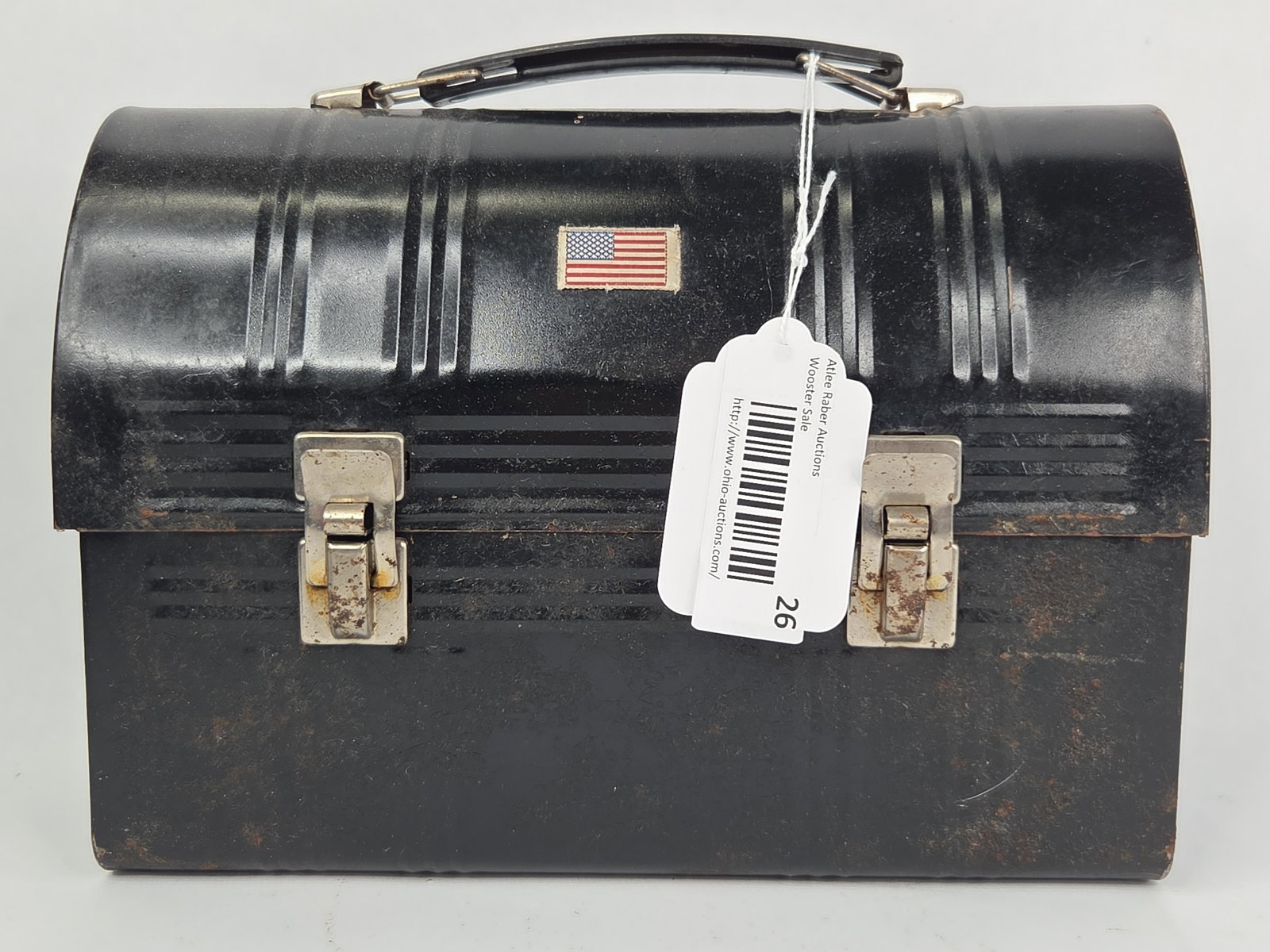 Aladdin Industries Metal Dome-Top Lunch Box with Thermos: This dome-top metal lunch box is manufactured by Aladdin Industries, Inc. of Nashville, Tennessee. The exterior is finished in black paint and features a small fabric American flag patch centered on