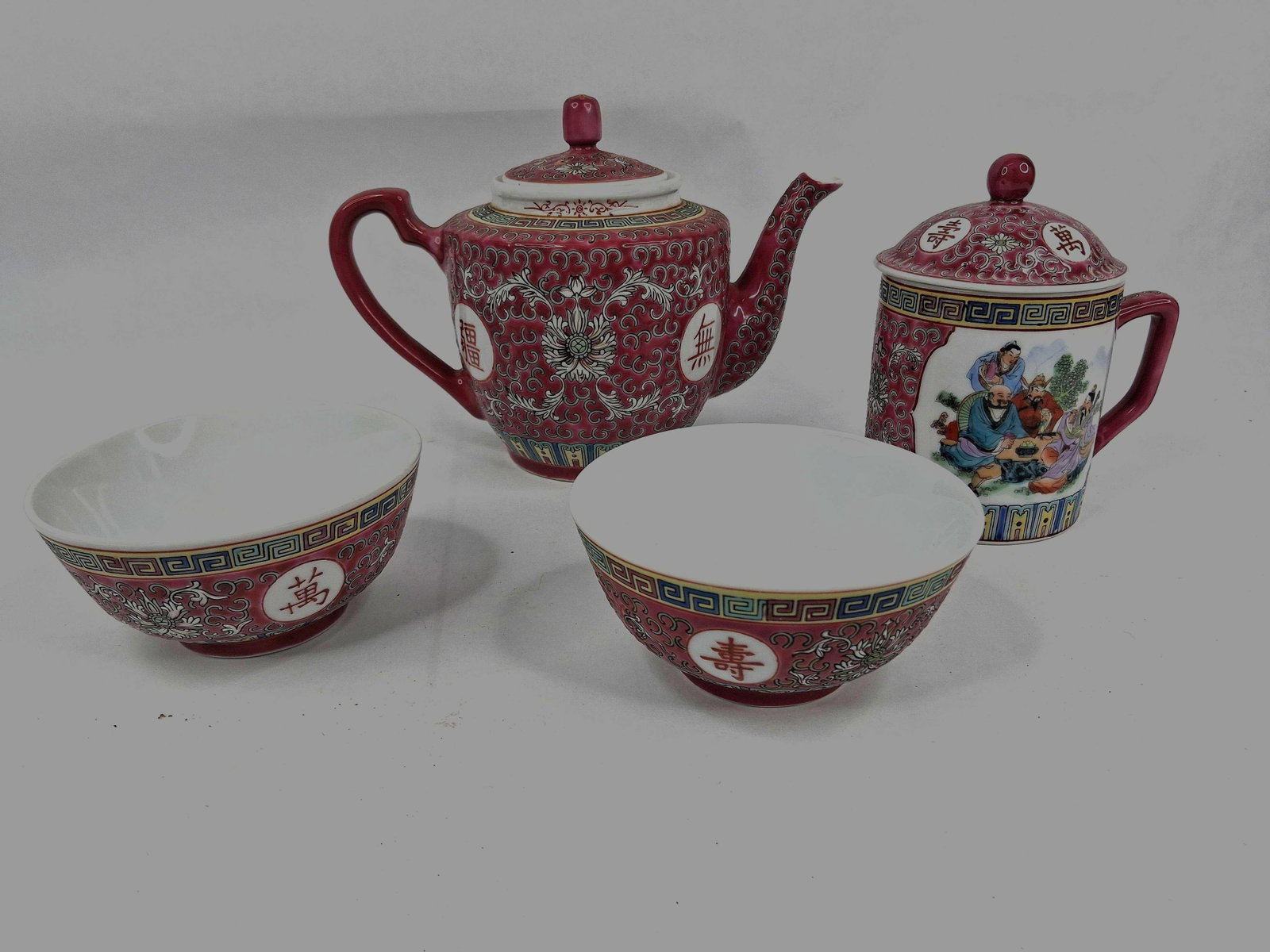 Set Chinese Mun Shou Pattern Porc. Tea & Serveware: This set of porcelain serveware features the Mun Shou pattern, a well-known variation of the famille rose style produced for export. The collection includes a teapot with its lid, a lidded mug, and tw
