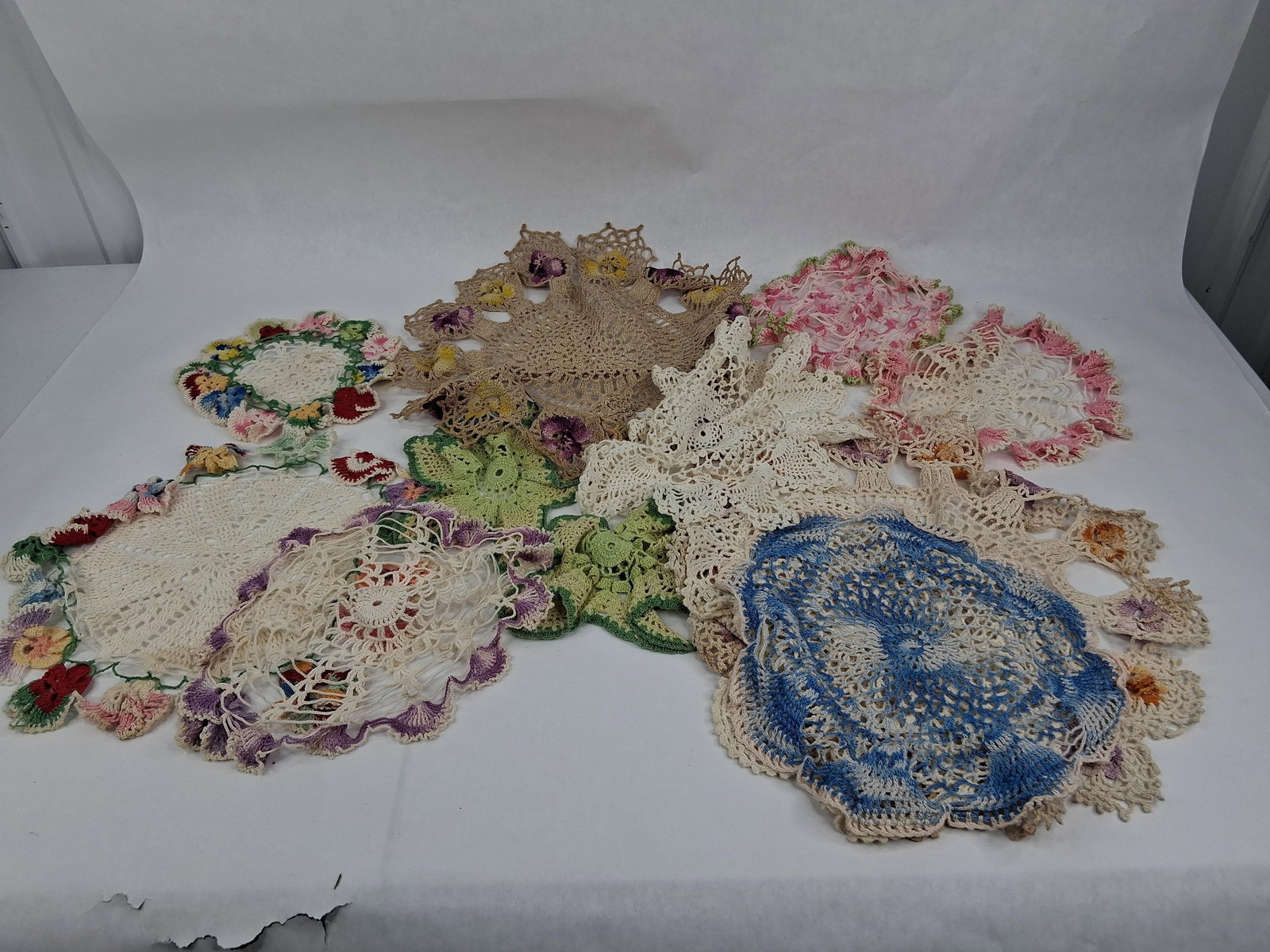 Set Colorful Hand Crocheted Doilies: An assortment of hand-crocheted doilies dating from the mid-20th century, approximately 1940s to 1960s. The collection is constructed from cotton crochet thread and showcases various traditional