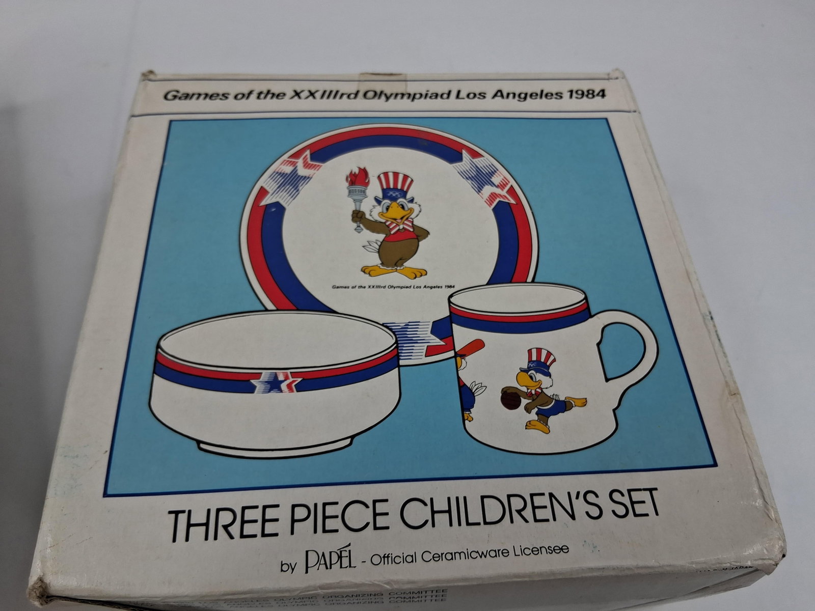 Papel 1984 LA Olympic Sam Eagle Ceramic Dinnerware: This three piece children's dinnerware set is an official licensed product for the Games of the XXIIIrd Olympiad, held in Los Angeles in 1984. Manufactured by Papel, the set is made of white ceramic