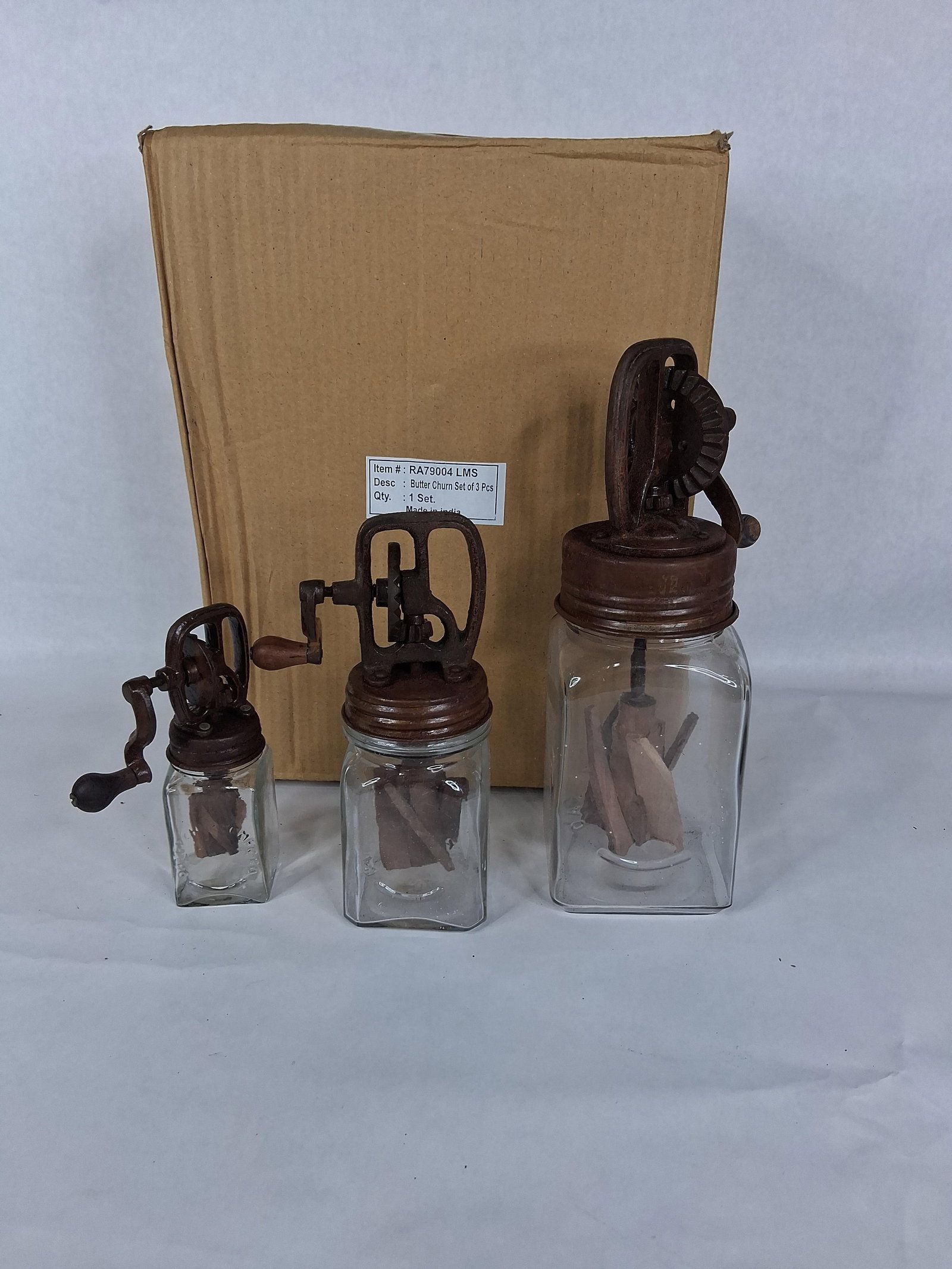 Set 3 Dazey Style Glass & Cast Iron Butter Churns: A set of three decorative butter churns in graduated sizes, designed in the style of antique Dazey glass churns. Each piece features a clear glass jar with a rectangular footprint and molded lettering