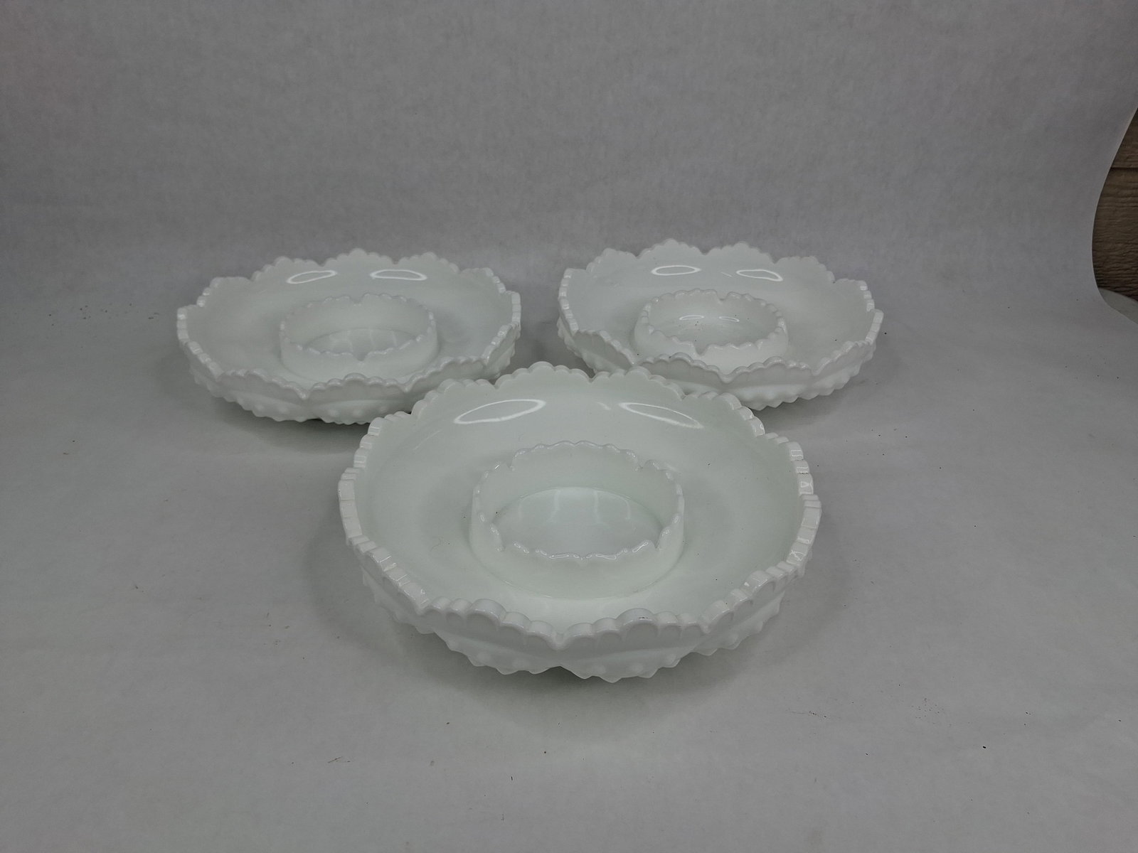 3 Fenton Hobnail Milk Glass Scalloped Edge Bowls: This collection consists of three opaque white milk glass bowls produced by the Fenton Art Glass Company in the signature Hobnail pattern. Each circular bowl is designed with an integrated raised