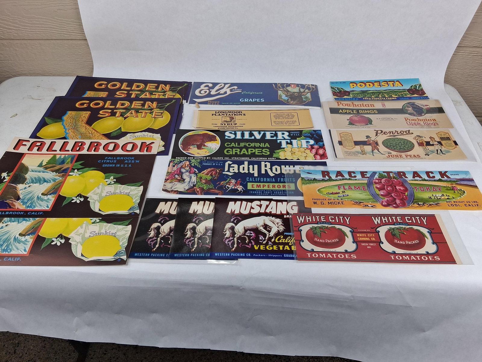 American Fruit & Vegetable Crate & Can Labels: This lot comprises a collection of approximately 17 original lithographic labels used for agricultural crates and canned goods, primarily dating from the early to mid-20th century. The collection