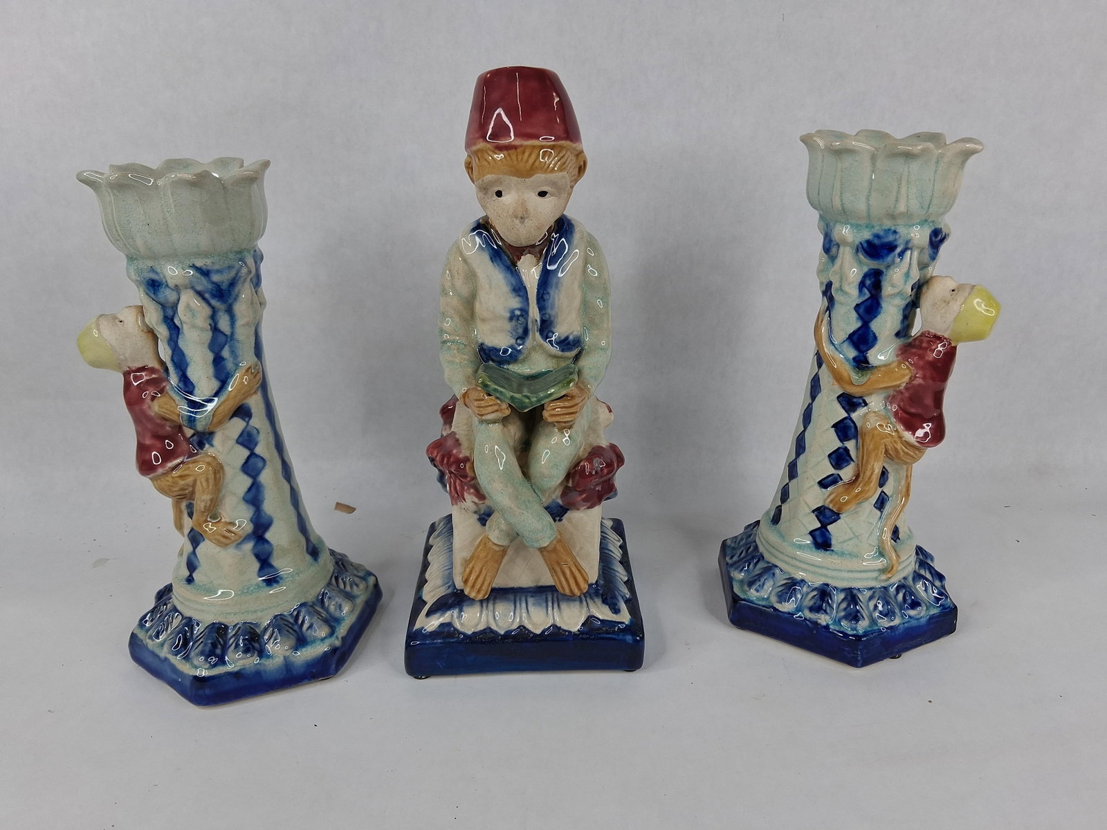 Danny Trio Glazed Ceramic Monkey Garnitures: 10 in tall A trio of mid-century glazed ceramic monkey garniture pieces featuring the incised mark of Danny. The set consists of a central seated figure and a matching pair of candlesticks, all