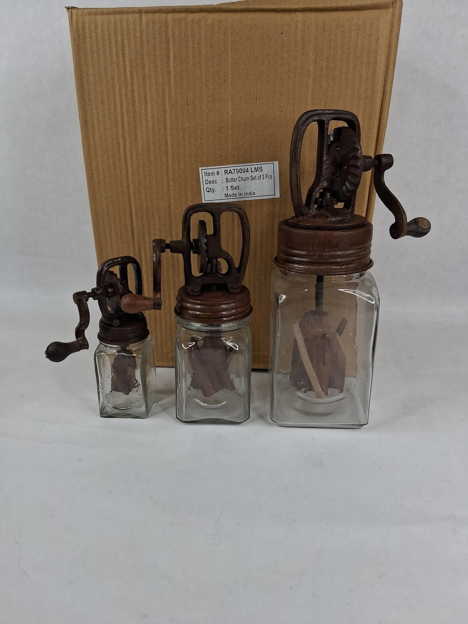 Set 3 Glass & Cast Iron Butter Churns: A set of three decorative clear glass butter churns in graduated sizes, designed as modern reproductions of antique Dazey models. Each churn features a square glass jar with rounded corners and