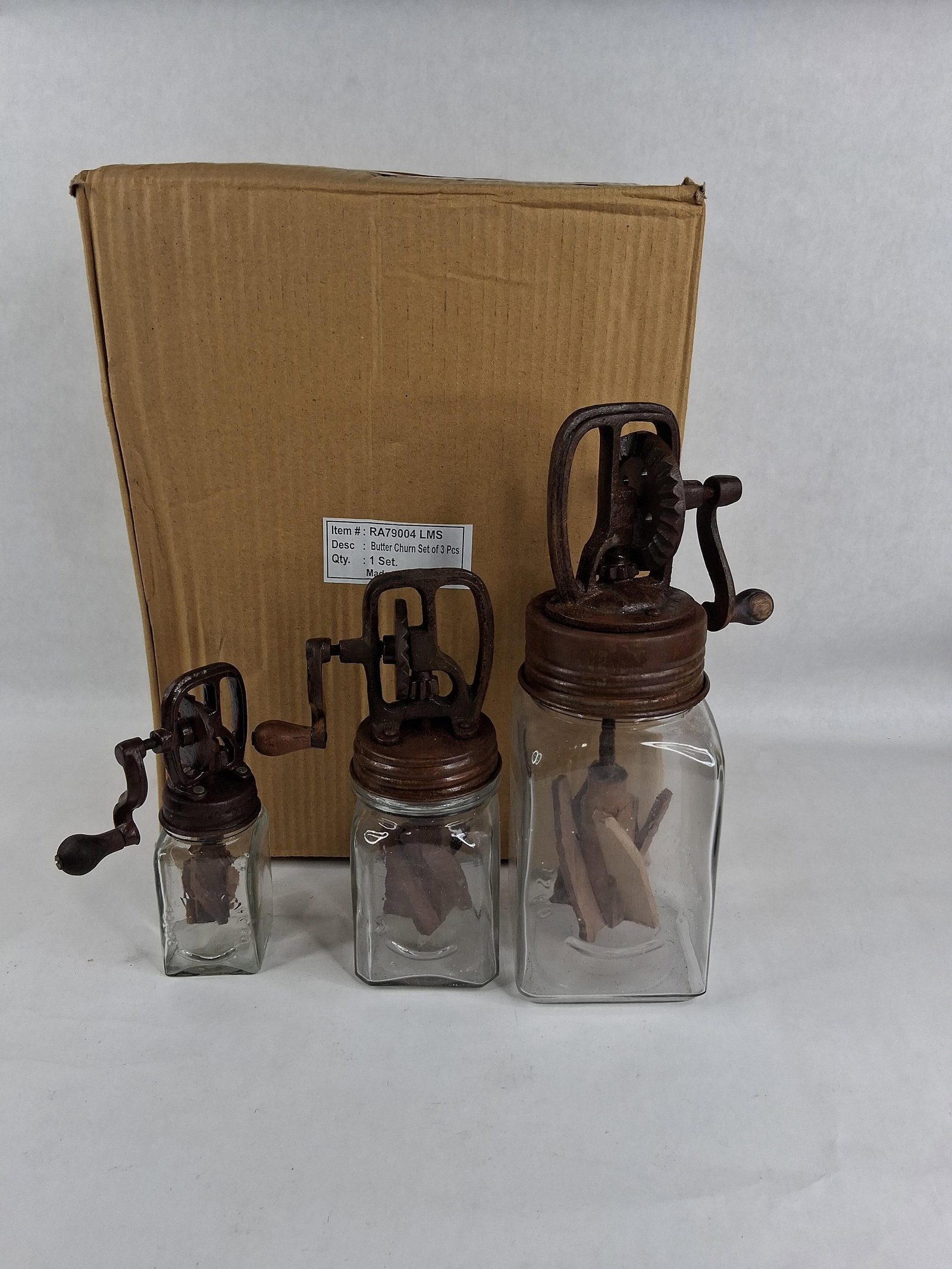 Set 3 Dazey Style Reproduction Glass Butter Churns: This collection includes a three piece set of reproduction glass jar butter churns in graduated sizes. Each unit consists of a clear glass jar with a square body featuring embossed DAZEY and CHURN
