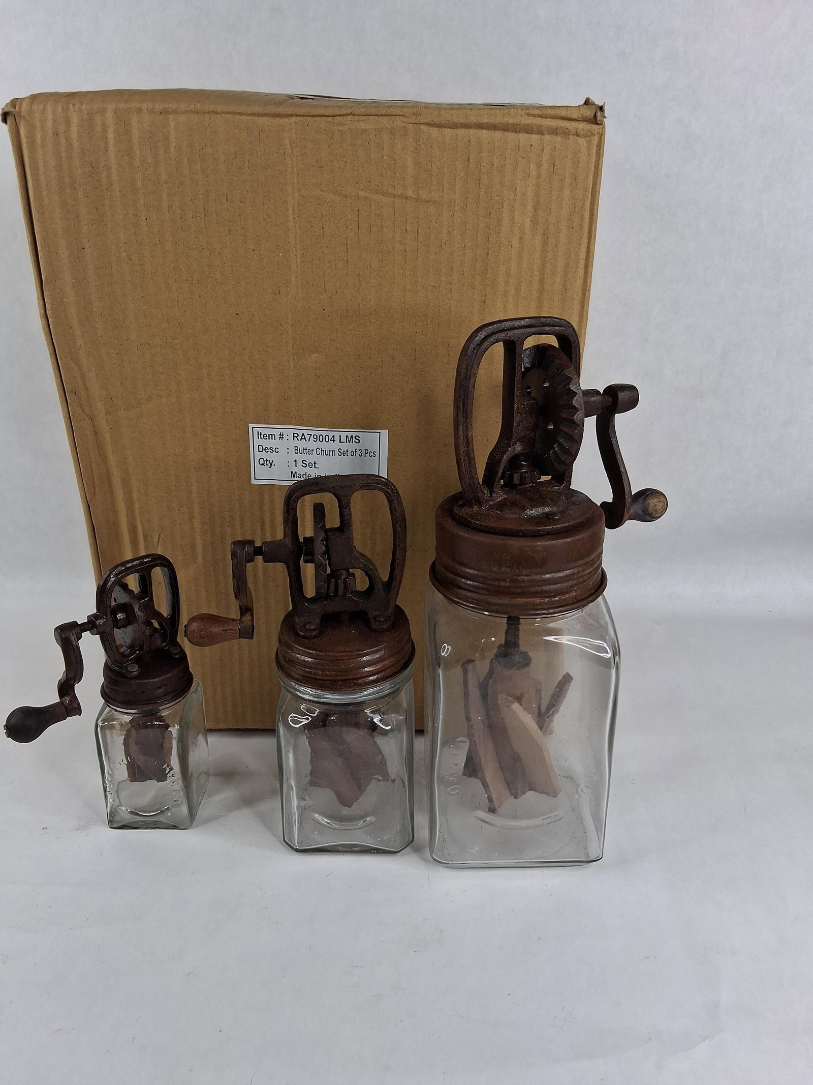 A Set of Three Modern Reproduction Dazey Style Glass and Cast Iron Butter Churns: This lot consists of a set of three graduated tabletop hand-crank butter churns, produced as modern decorative reproductions of early 20th-century designs. Each churn is constructed with a square-prof